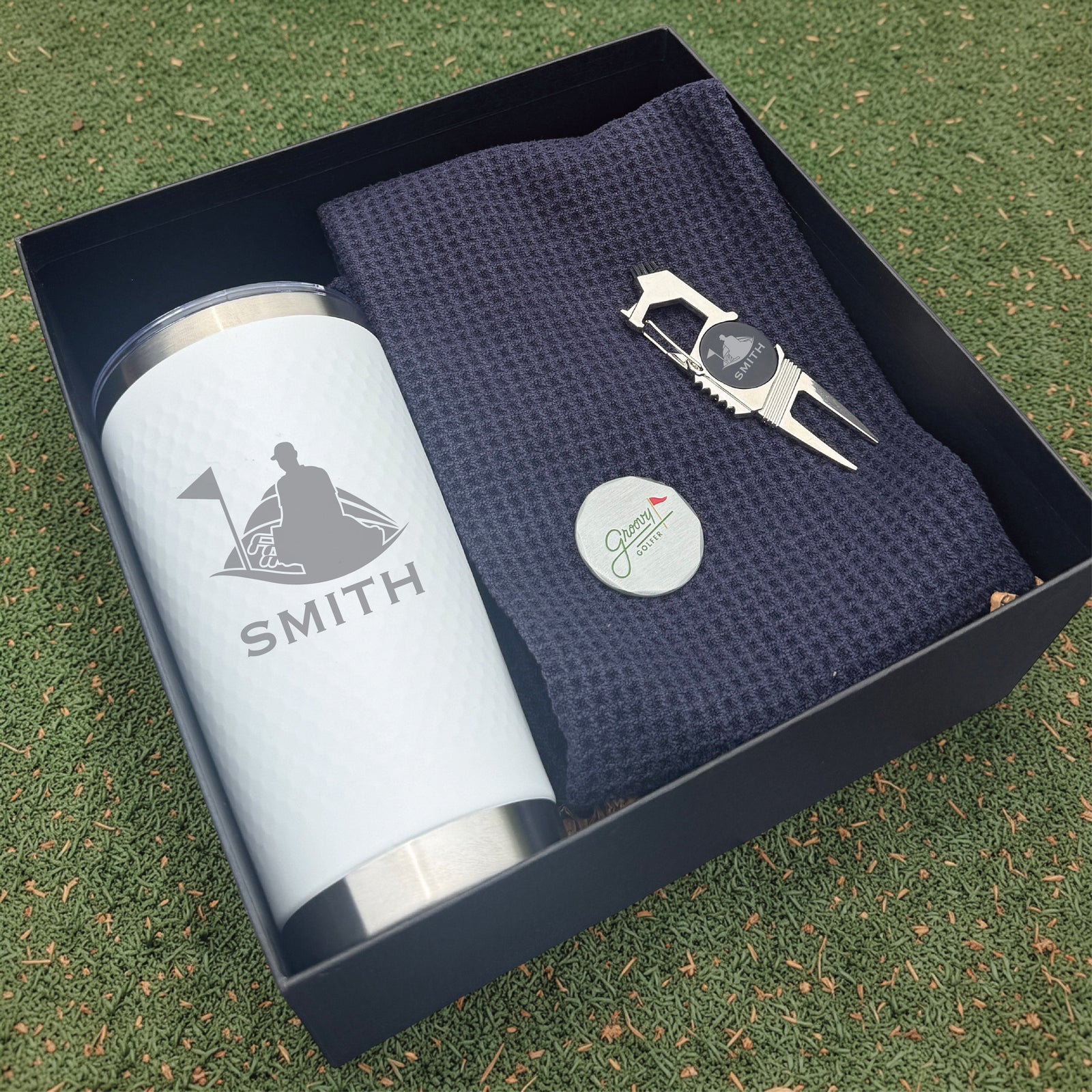 Personalized golf gift box containing an insulated tumbler, a waffle golf towel and a divot tool with a magnetic ball marker, engraved with a name