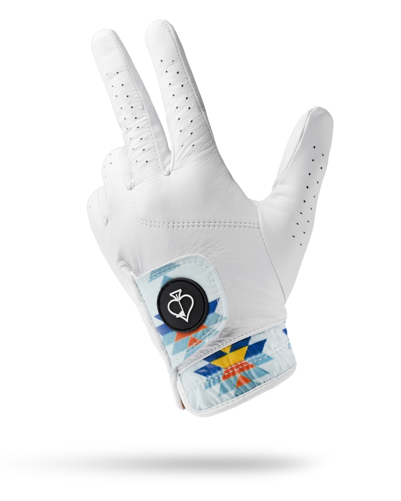 White leather golf glove with perforated fingers, geometric blue and orange patterned cuff band, and black magnetic ball marker emblem on the wrist.