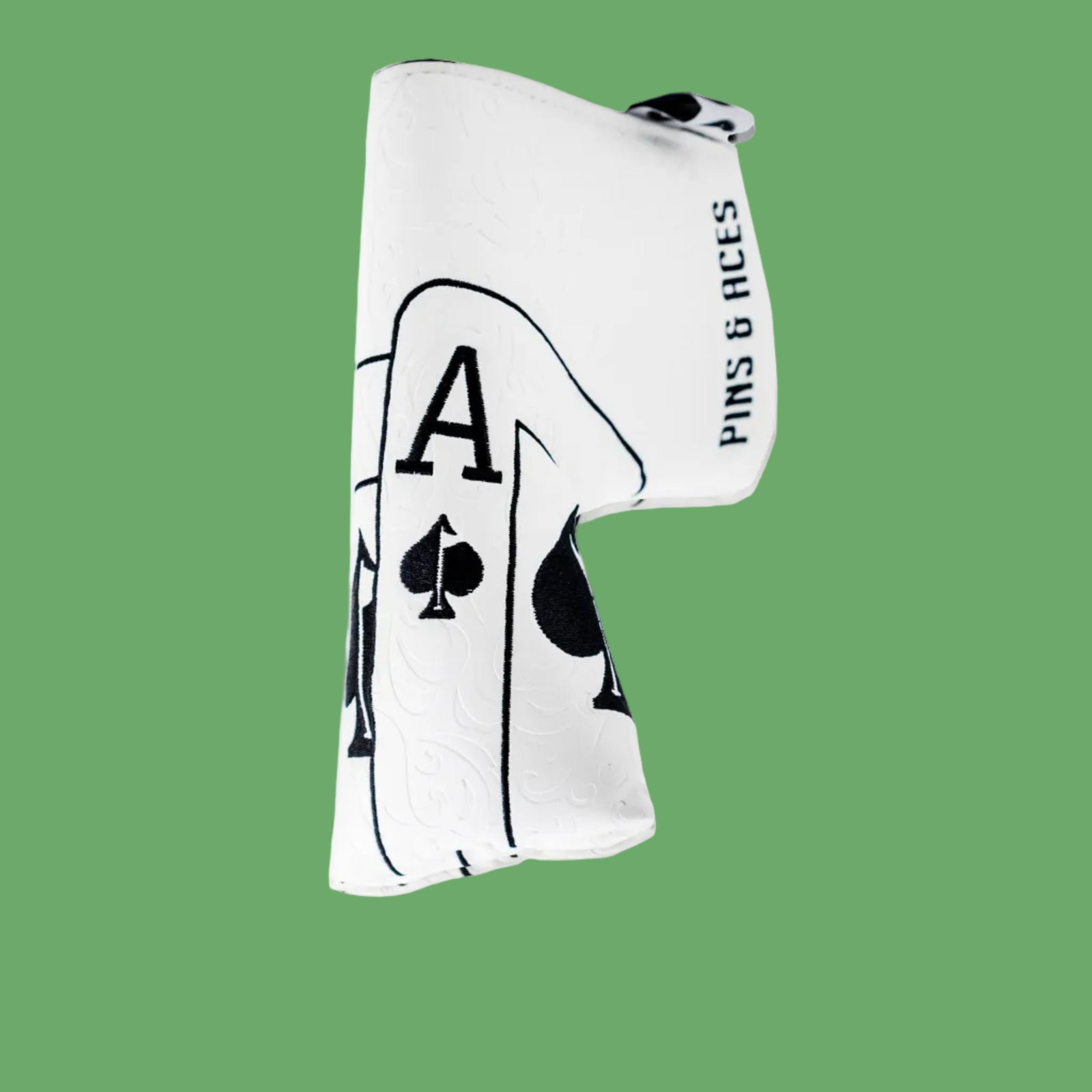 White putter blade cover with embroidered Ace of Spades symbol and "Pins & Aces" text on side, shown at angle against green background