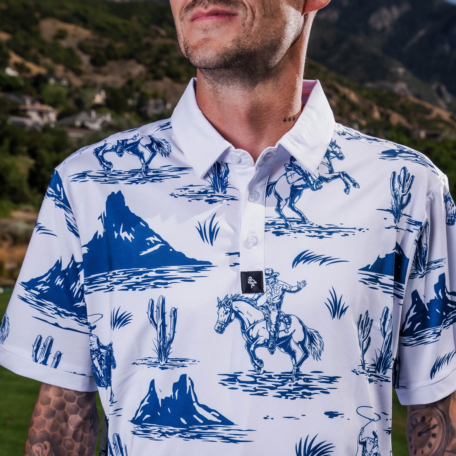 Men’s white polo with blue cowboy hats, boots & lasso print – Western-inspired, breathable, and stretch-performance-ready.