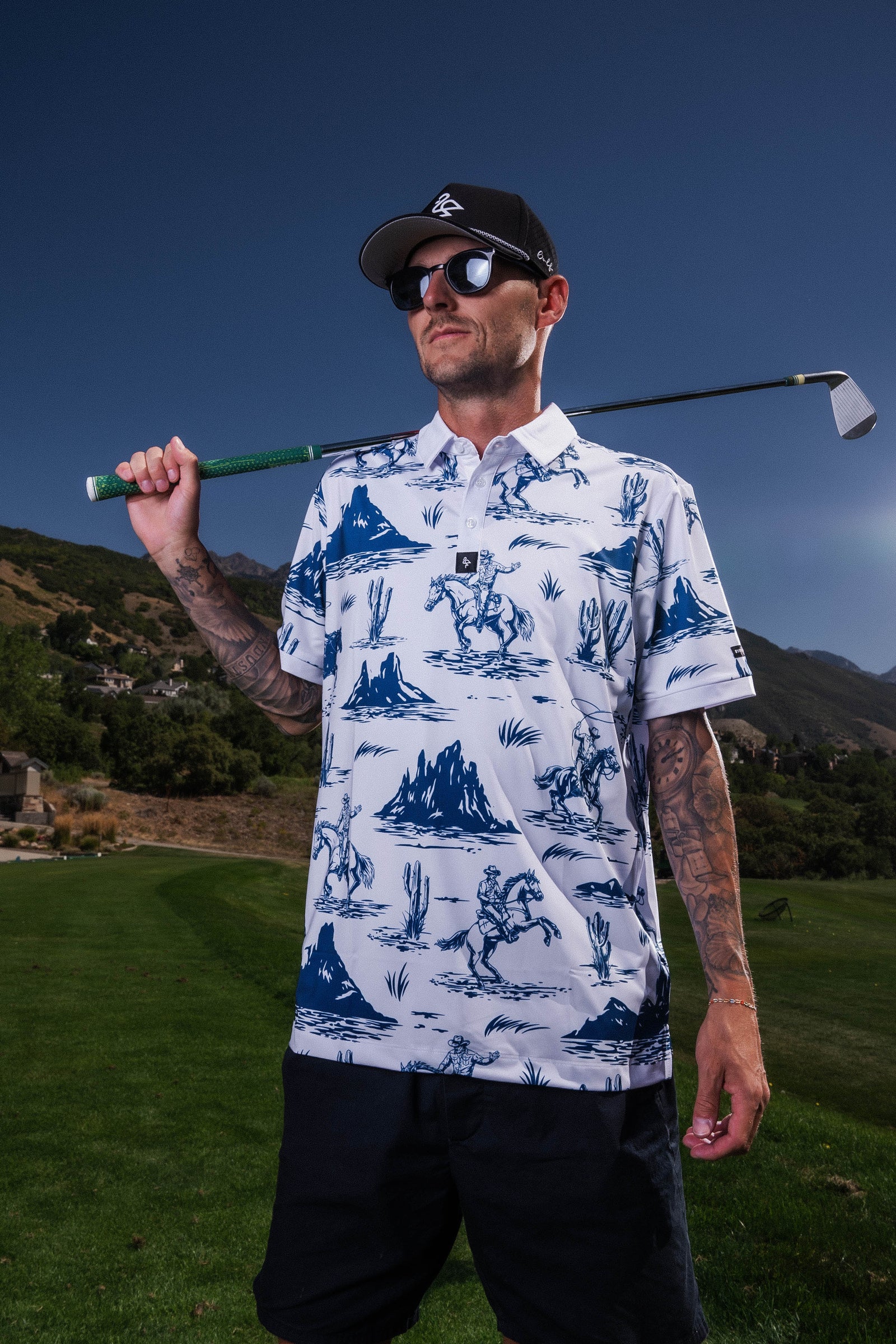 Men’s white polo with blue cowboy hats, boots & lasso print – Western-inspired, breathable, and stretch-performance-ready.