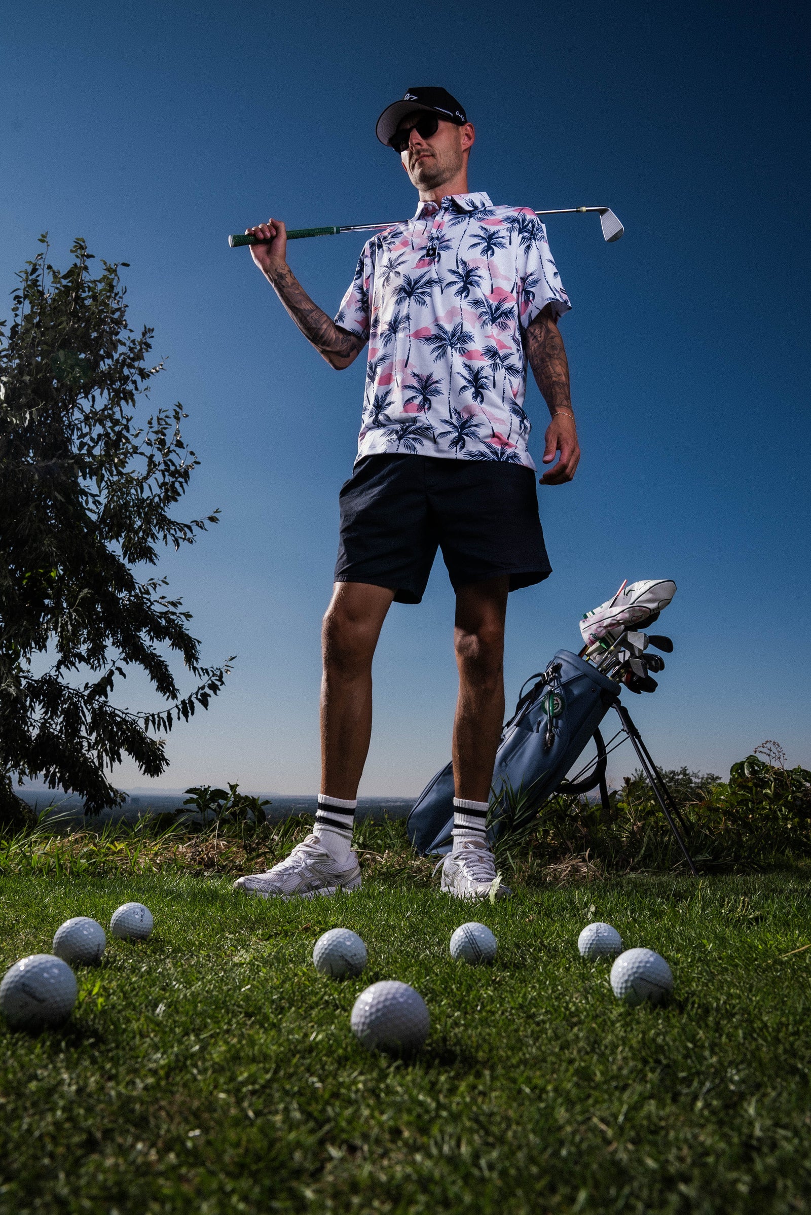 Men’s white polo with vibrant green and pink palm tree print – tropical feel with stretch, moisture control, and wrinkle resistance.