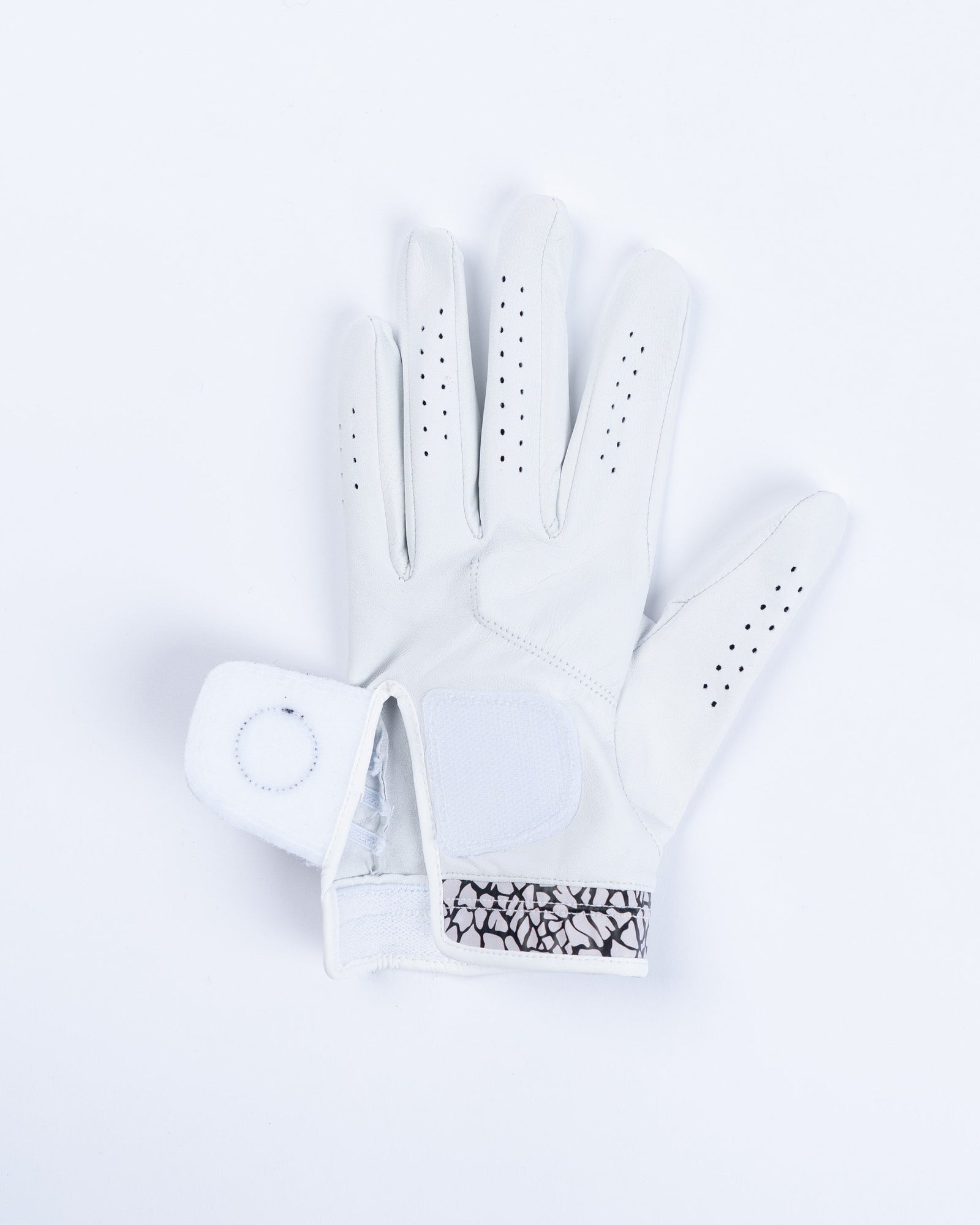 White Cabretta leather golf glove with perforated fingers and bold black elephant print cuff detail, shown flat lay from palm side