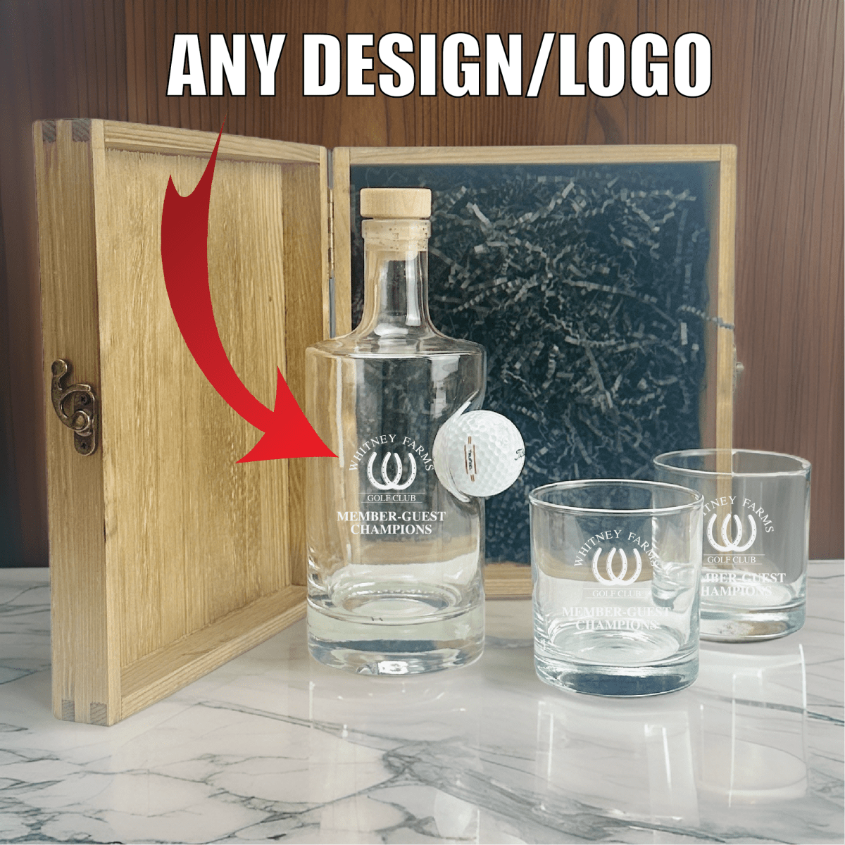 Wooden gift box with engraved sample logo "Whiney Farms Golf Club Member-Guest Champions" displayed open, showing decanter with embedded golf ball and two matching glasses