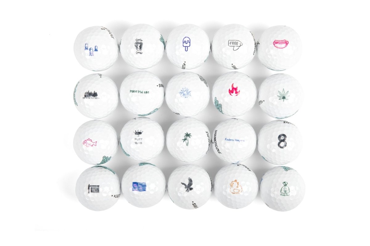 Collection of white golf balls displayed in a grid, each stamped with different colorful designs including icons, text, animals, and symbols in blue, pink, and teal ink.