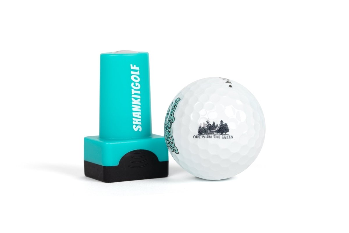 Turquoise and black ball stamper next to white golf ball printed with sample forest tree design and "ONE WITH THE TREES" text