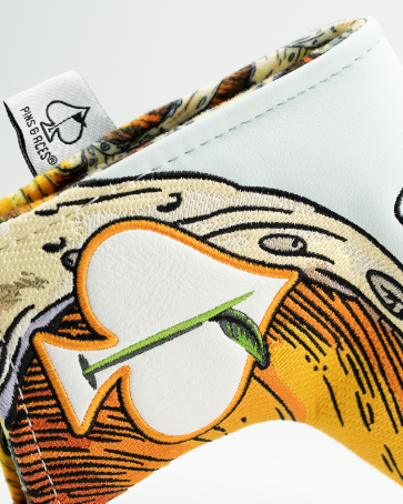 Screwdriver putter headcover with embroidered cocktail design in orange and yellow, shown alongside matching feathered golf tee with branded packaging.