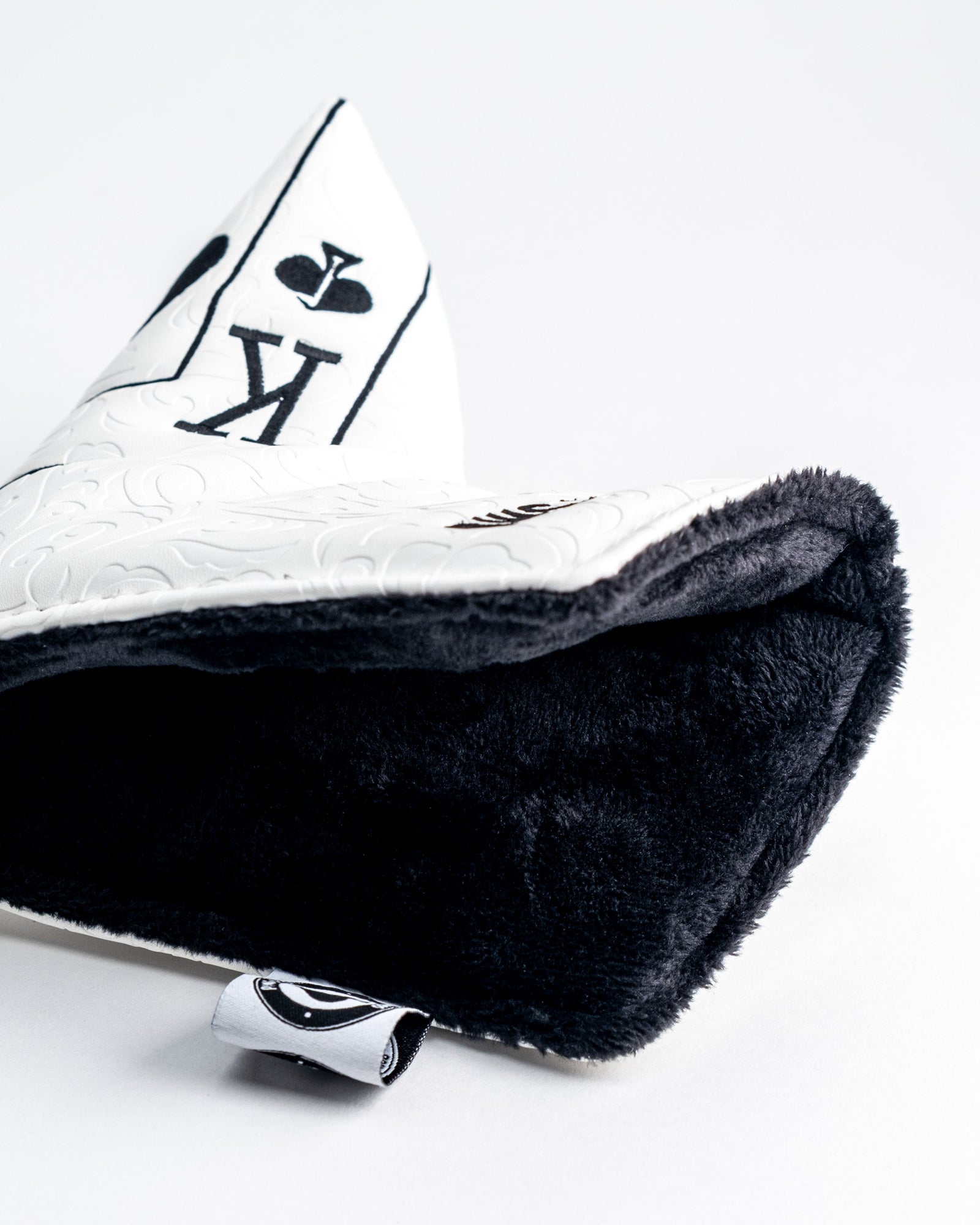 White putter blade cover with embroidered Ace of Spades design, shown folded with black fuzzy interior and embossed faux leather exterior