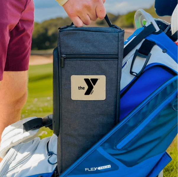 Dark blue insulated cooler bag with sample logo patch being held beside a blue golf bag on a course, with golfer in pink sleeve visible.