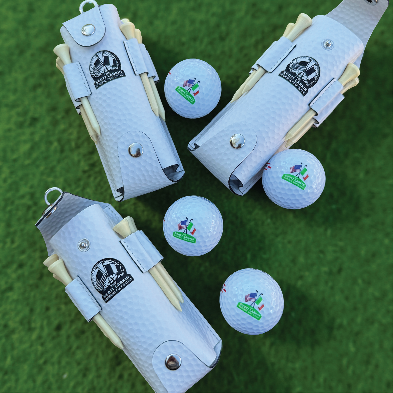 White textured pouch with sample logo and four golf balls printed with sample corporate logo and flag design, displayed on green grass with included wooden tees