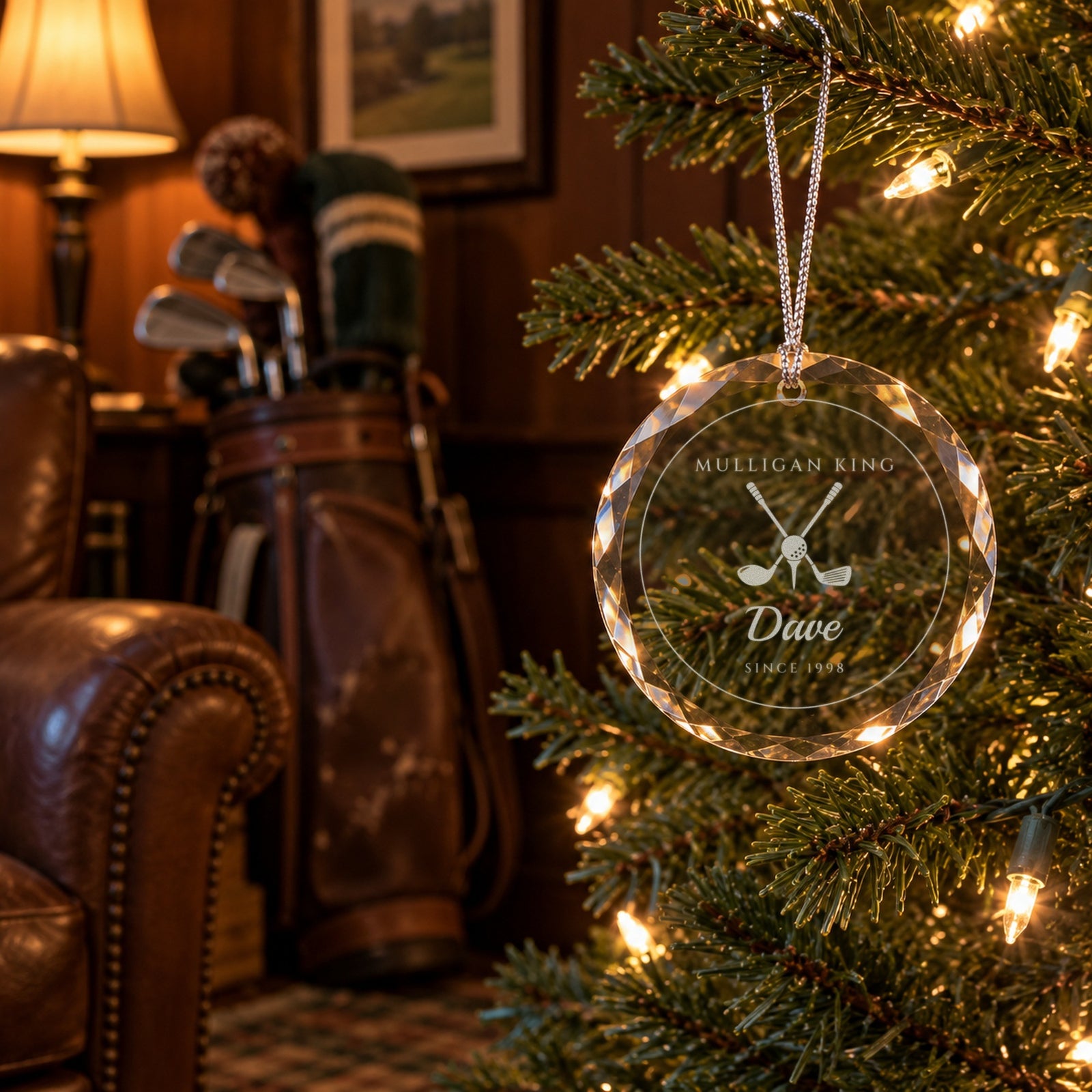 Golf Christmas ornament engraved MULLIGAN KING, Dave, SINCE 1998 hanging on a tree in a wood-paneled den with a leather golf bag behind it