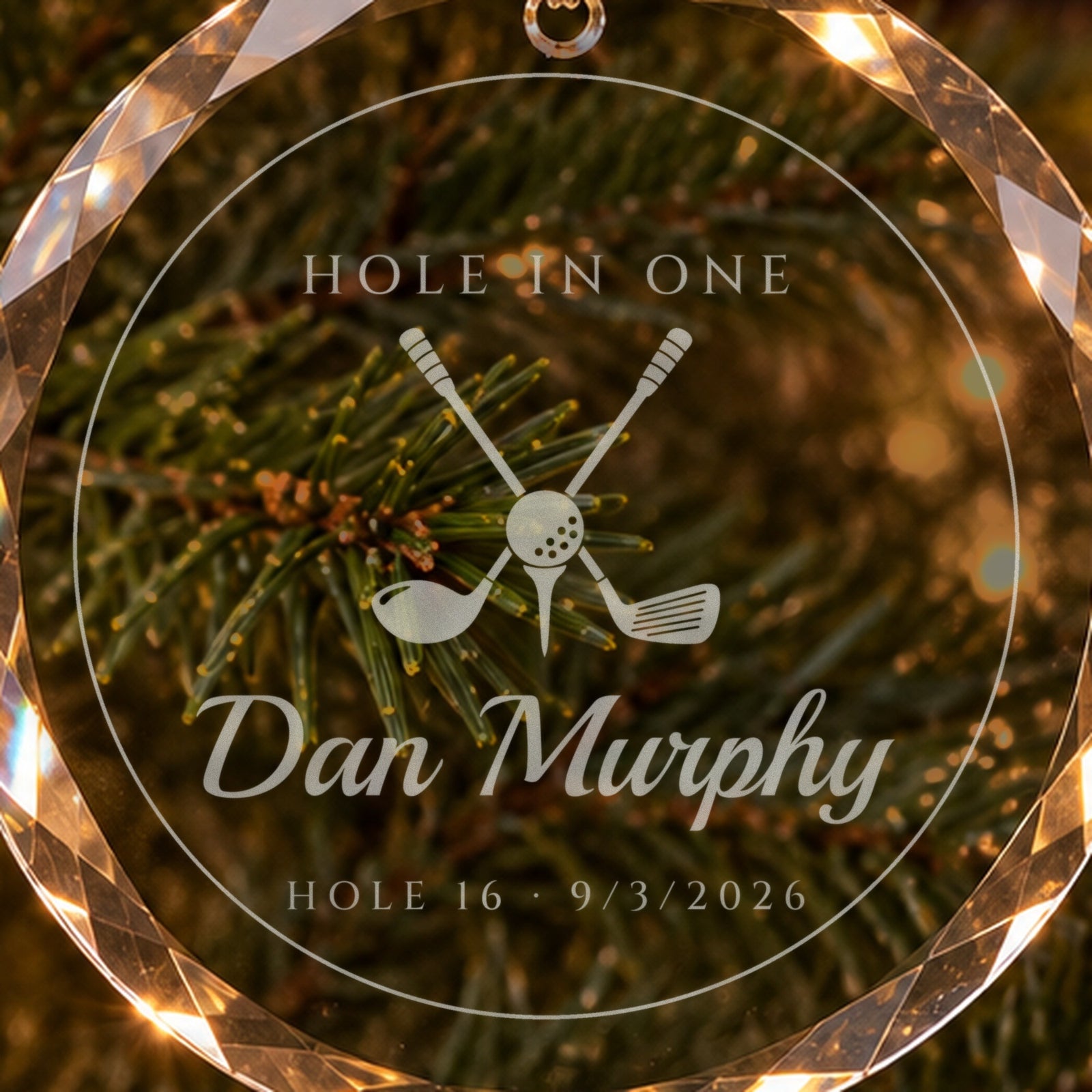 Close-up of the frosted engraving on the golf ornament: crossed driver and iron with a ball on a tee, HOLE IN ONE, Dan Murphy, HOLE 16, 9/3/2026