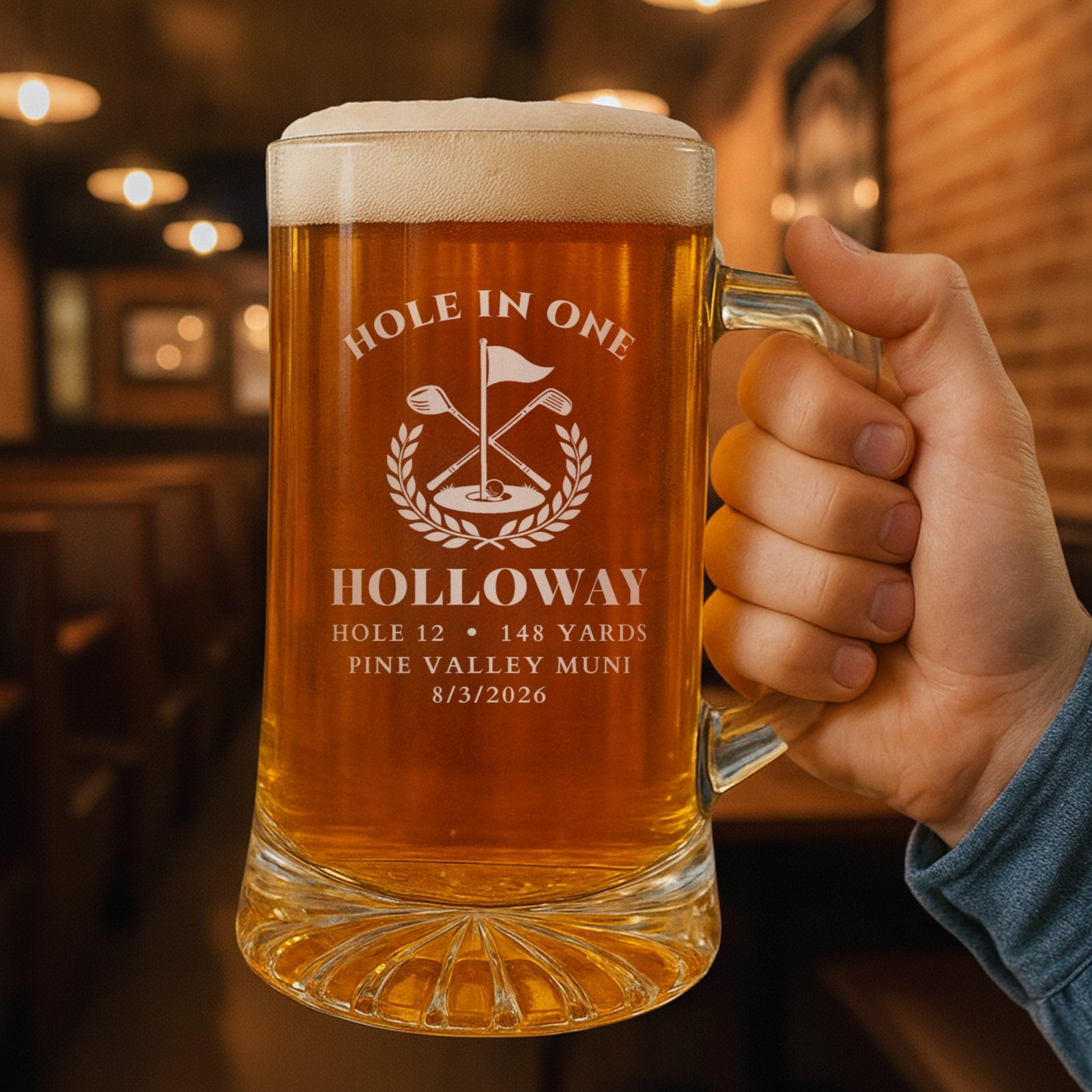 Hand holding the personalized hole in one beer stein in a pub, engraved HOLE IN ONE with HOLLOWAY, hole 12, 148 yards and Pine Valley Muni