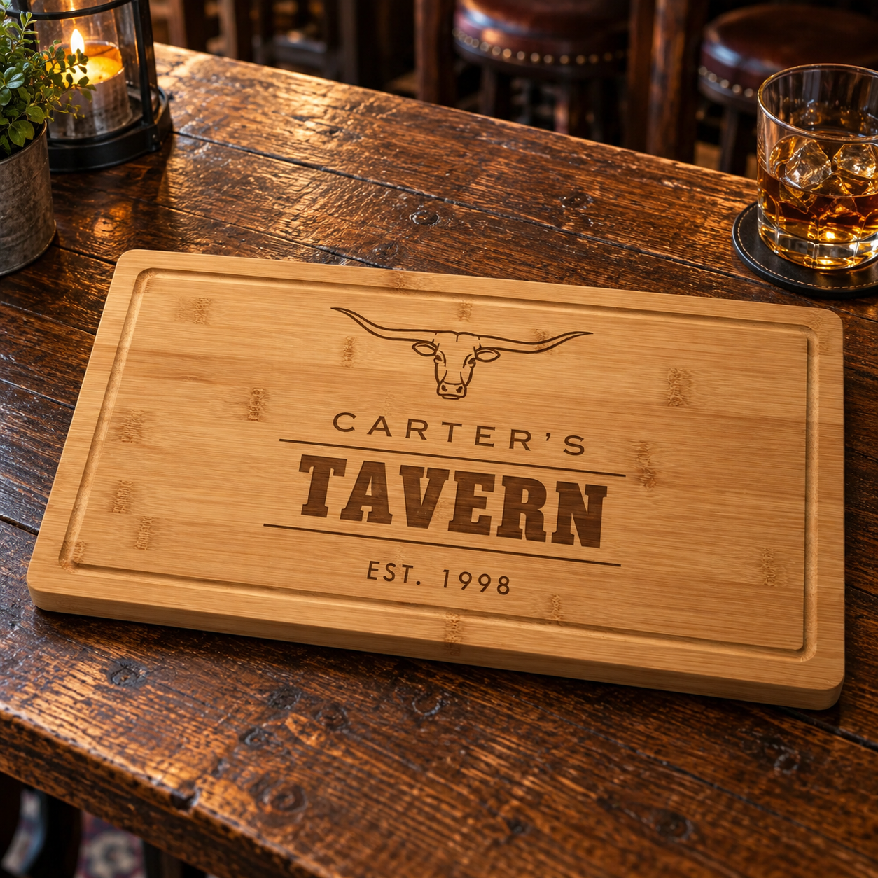 Bamboo steakhouse cutting board engraved Carter's Tavern Est. 1998 with a longhorn steer on a candlelit bar top, a personalized gift for a golfer
