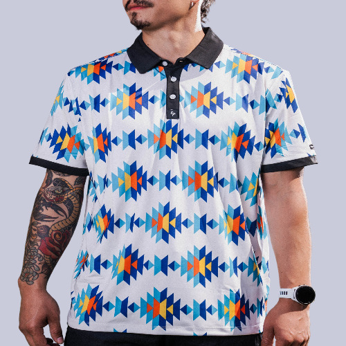 White Aztec polo with teal, orange &amp; navy diamond pattern, 4‑way stretch, UPF 50+, moisture‑wicking, anti‑odor &amp; wrinkle resistance.