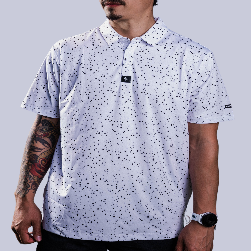 Men’s white polo with subtle grey-black dot “cosmic sprinkle” pattern—sleek, breathable, and performance-ready.