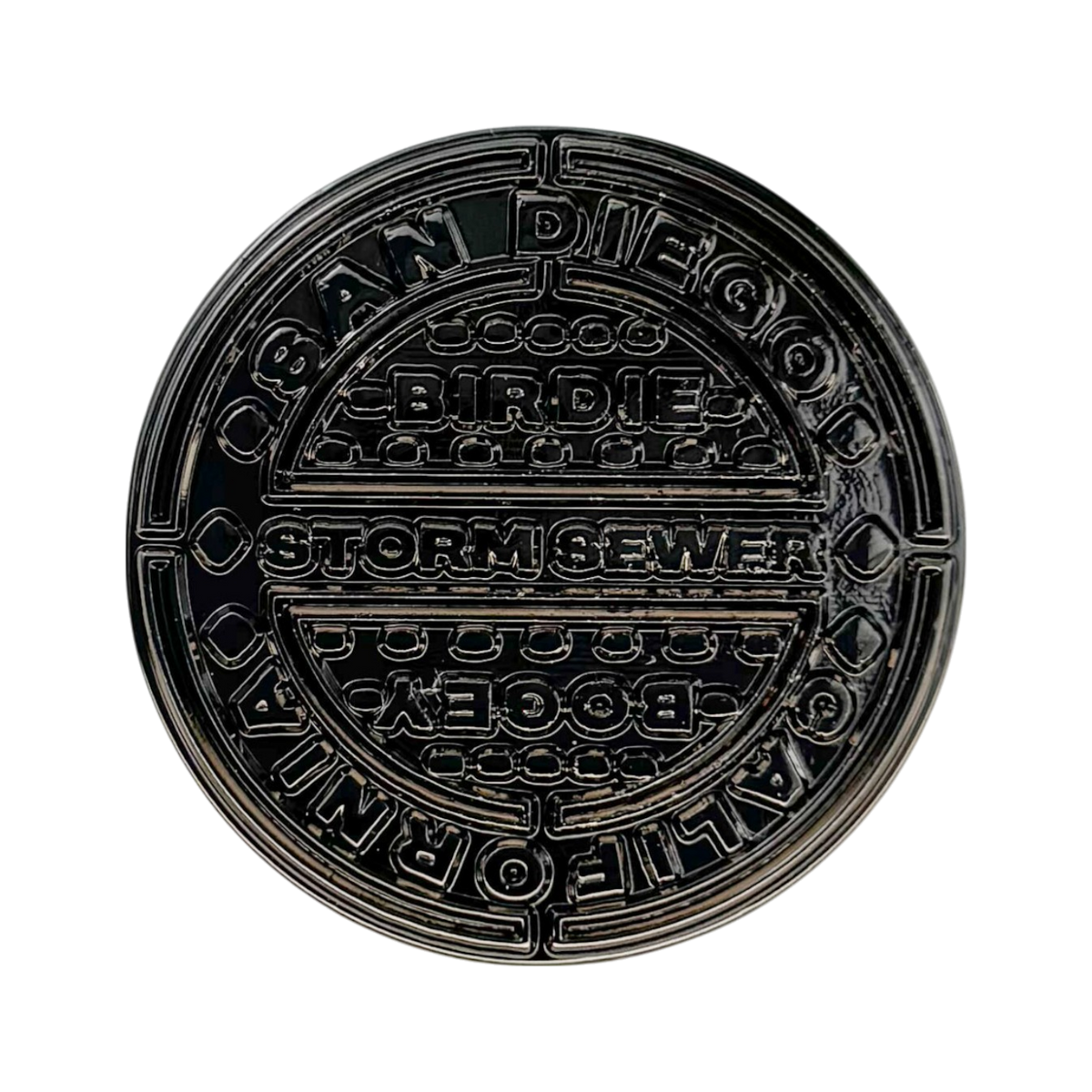 Manhole‑cover style golf ball marker with street‑wise texture and metal finish