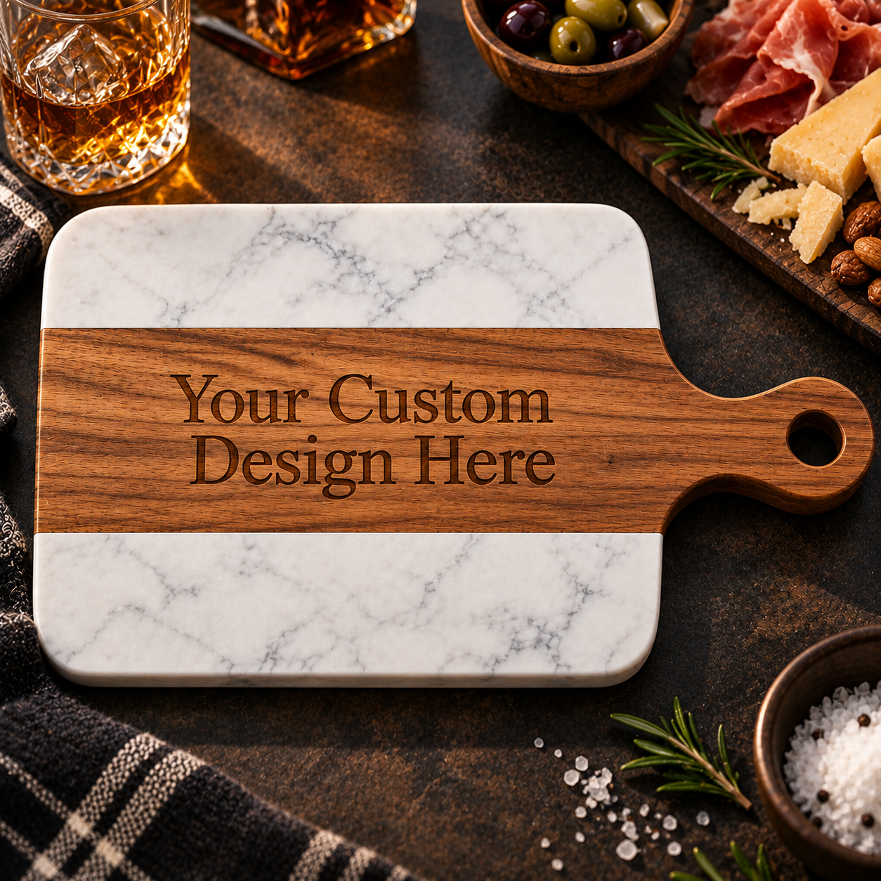 Custom wood and marble charcuterie board with "Your Custom Design Here" engraving, surrounded by whiskey glasses, olives, cured meats, and appetizers.