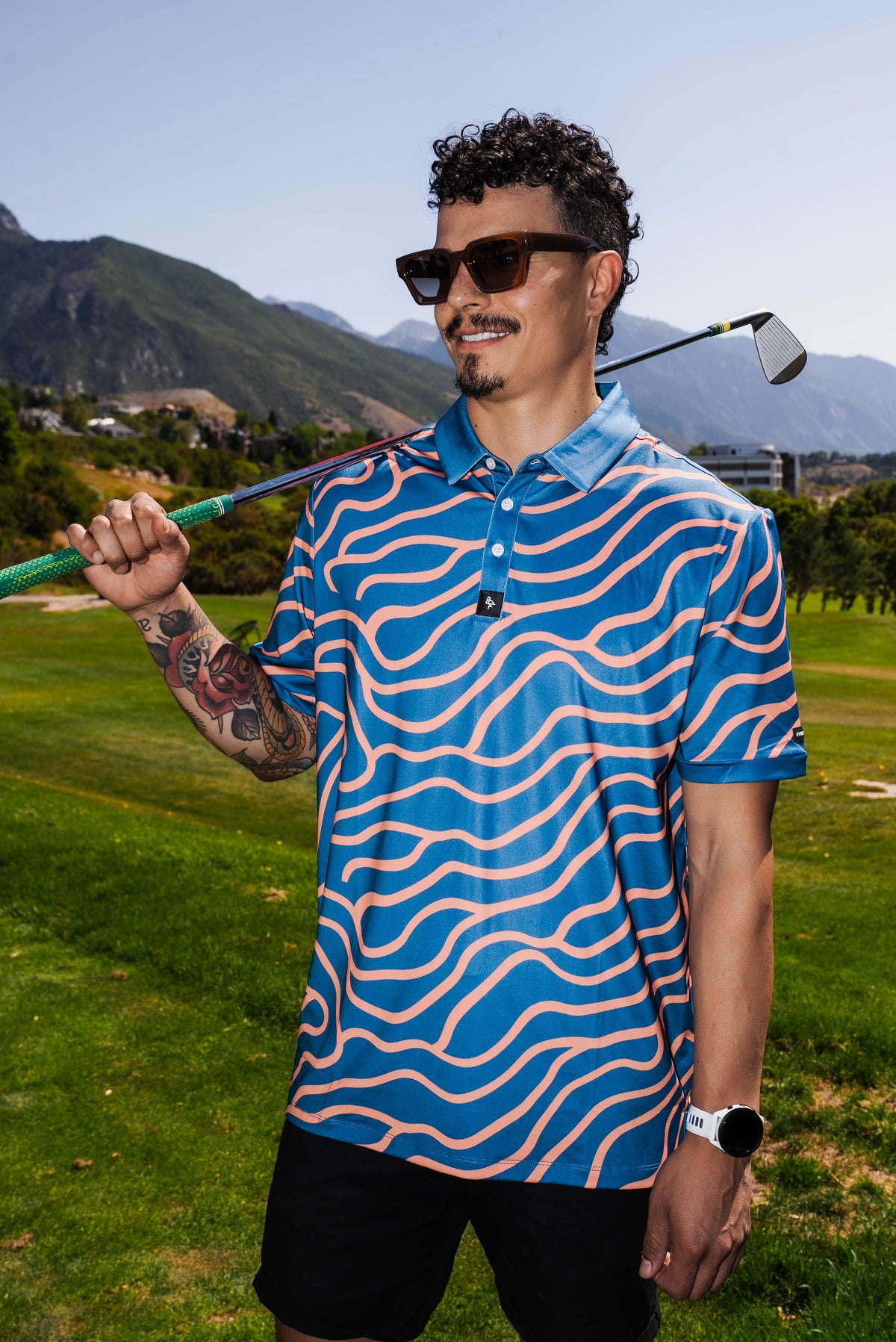 Men’s navy polo with peach wave-pattern print – dynamic, breathable, stretch-performance ready.