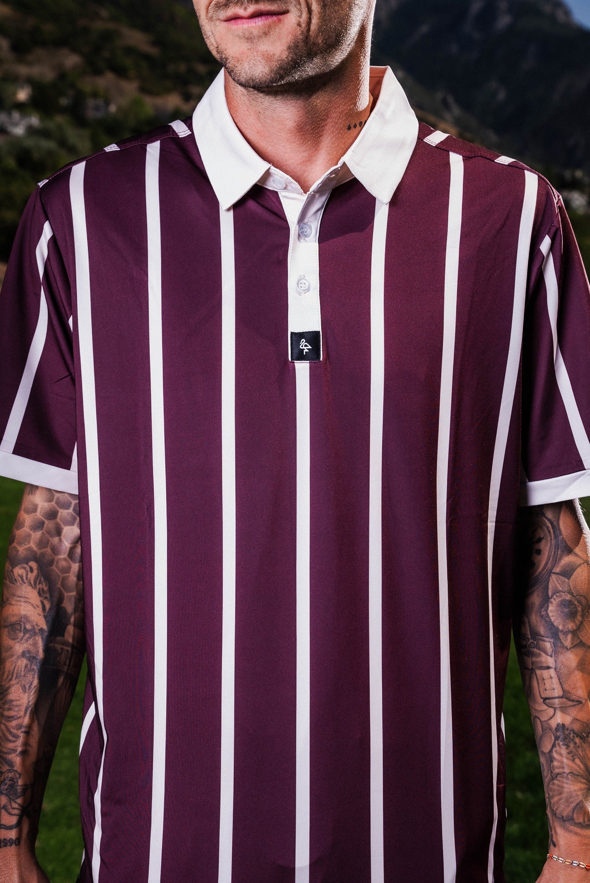 Men’s red and cream vertical stripe polo with crisp collar — varsity-inspired style with stretch, sun protection, and wrinkle resistance.