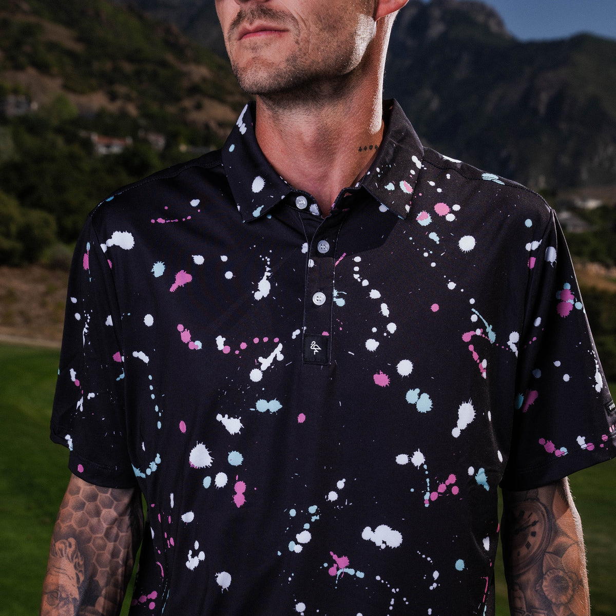Men’s black polo with gray-white drip-speck pattern – urban-inspired, breathable, stretch-performance ready.