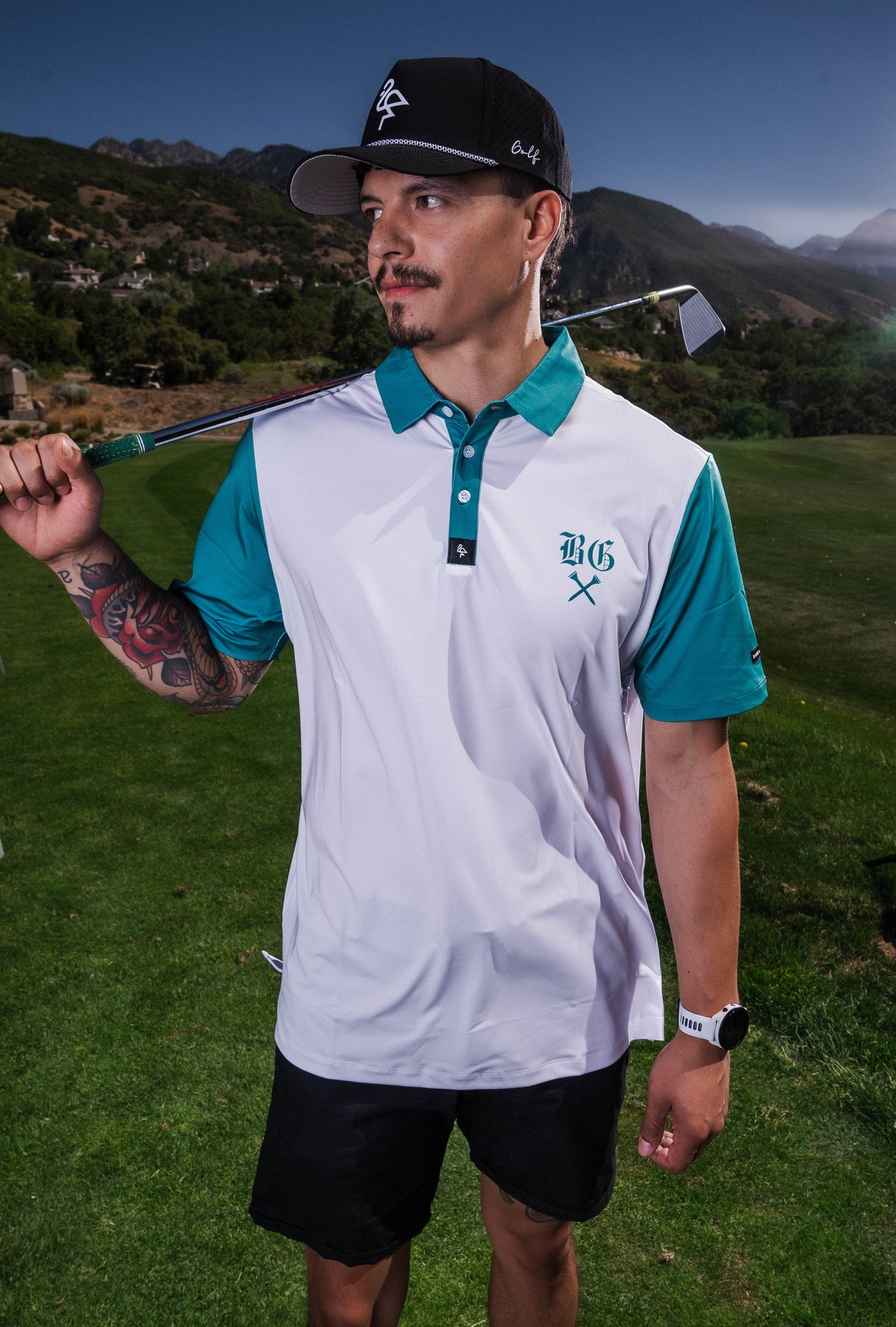 Men's white polo with green BG logo print – breathable, stretch fit with moisture control and wrinkle resistance.