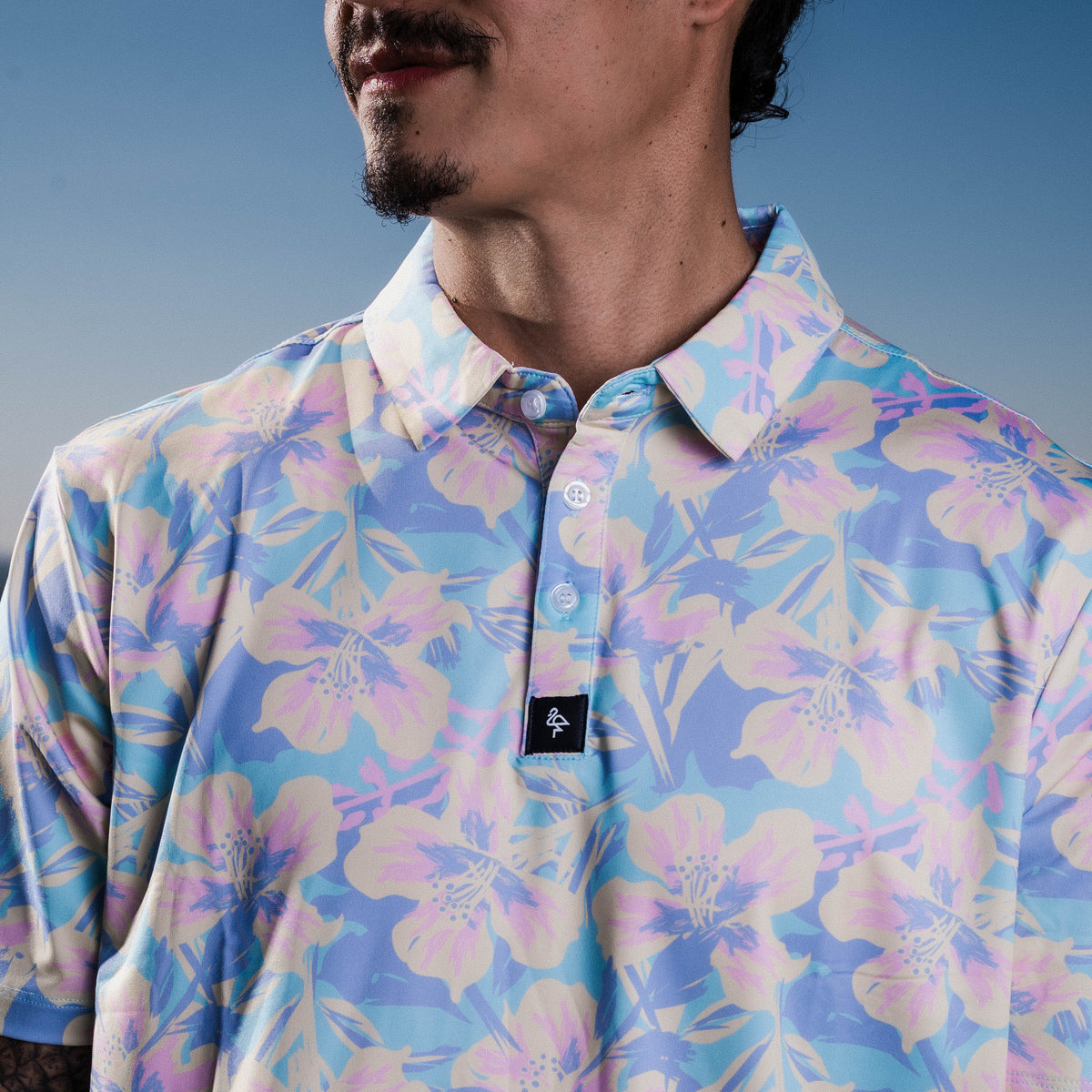 Men&#39;s off-white polo with pastel watercolor petal print – floral elegance with performance stretch and sun protection.
