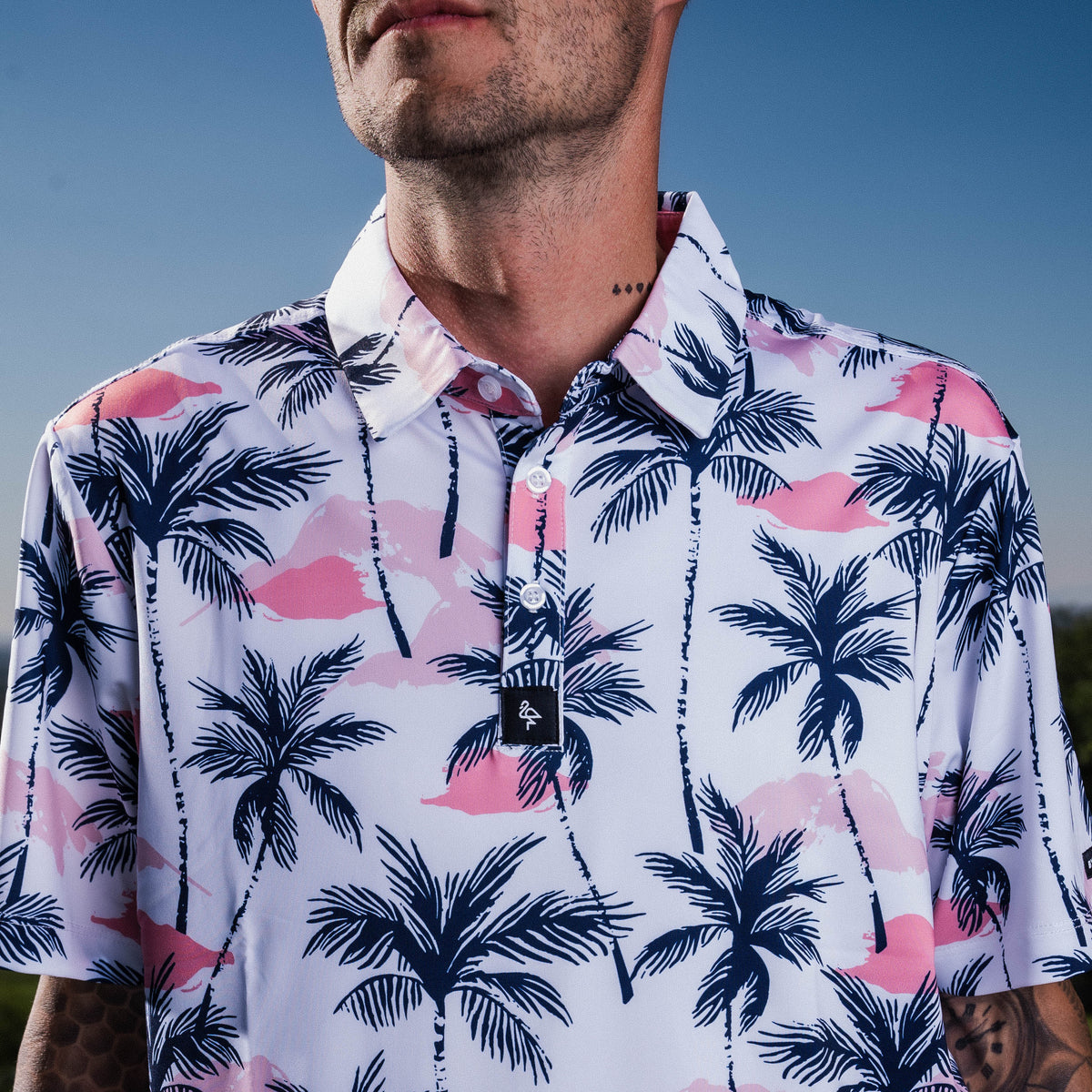 Men’s white polo with vibrant green and pink palm tree print – tropical feel with stretch, moisture control, and wrinkle resistance.