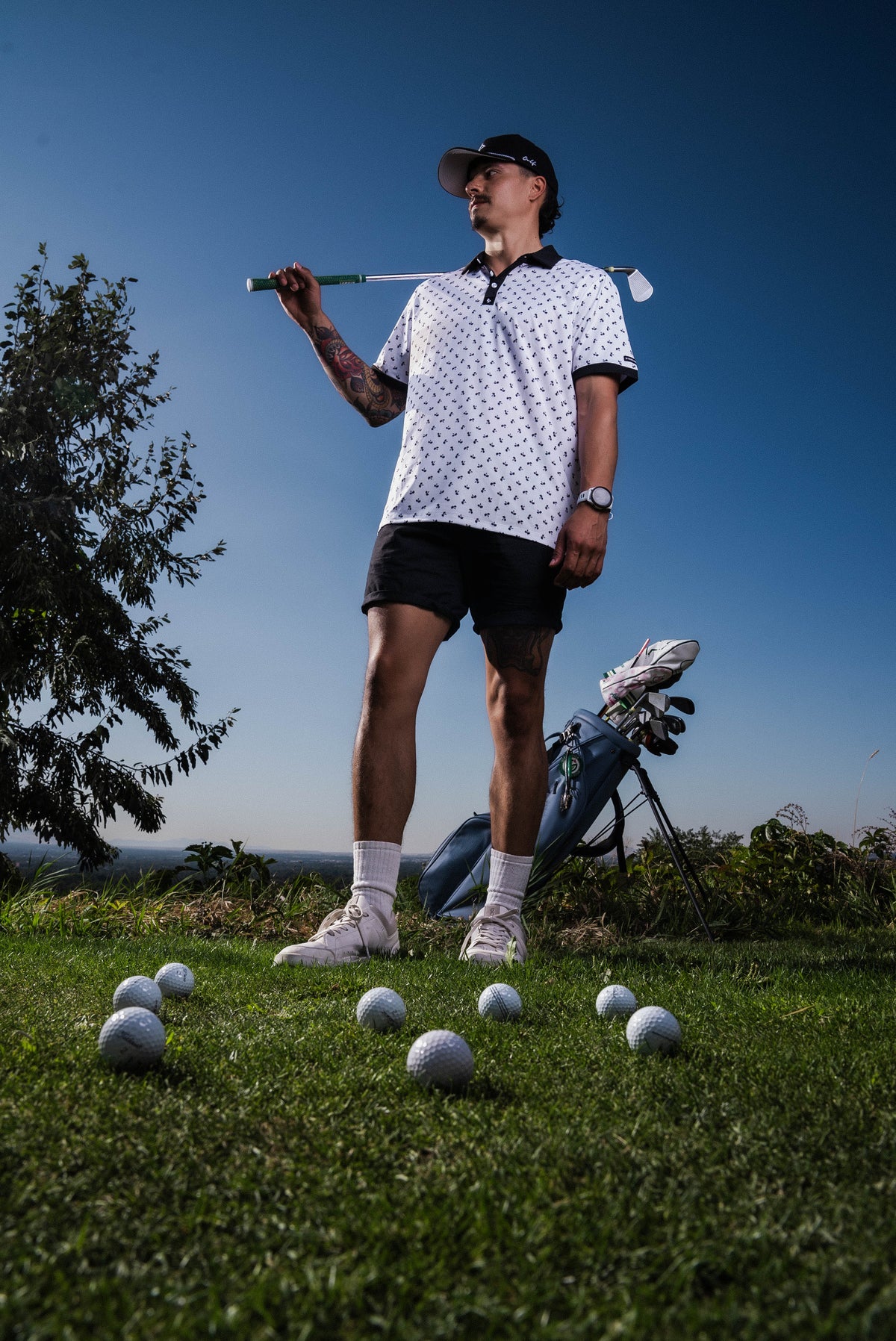 Men’s white polo with small navy palm leaf print and contrast collar – tropical-infused, stretch-performance ready.