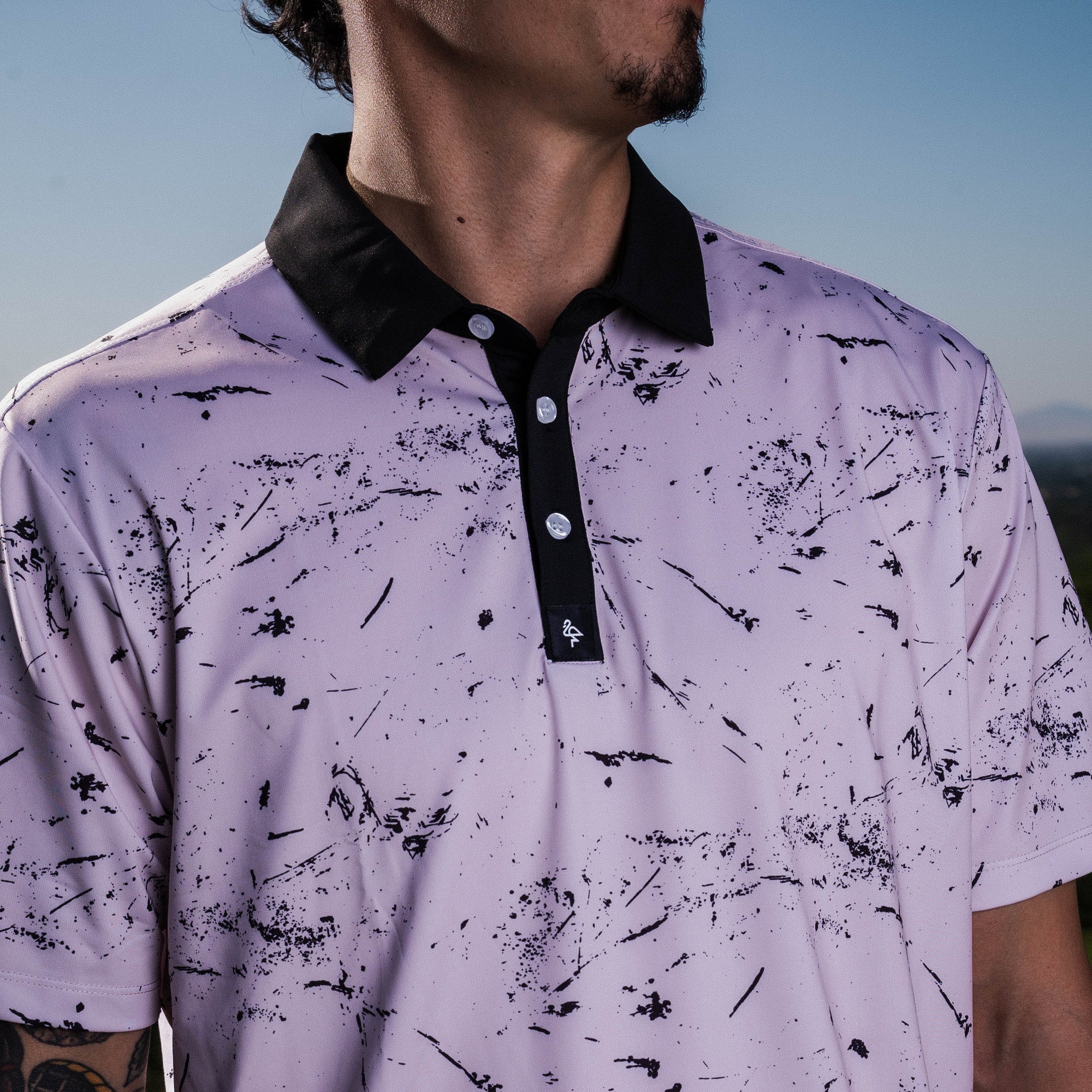 Men’s cream polo with subtle drip-splatter texture and contrast black collar—classic and breathable performance fit.
