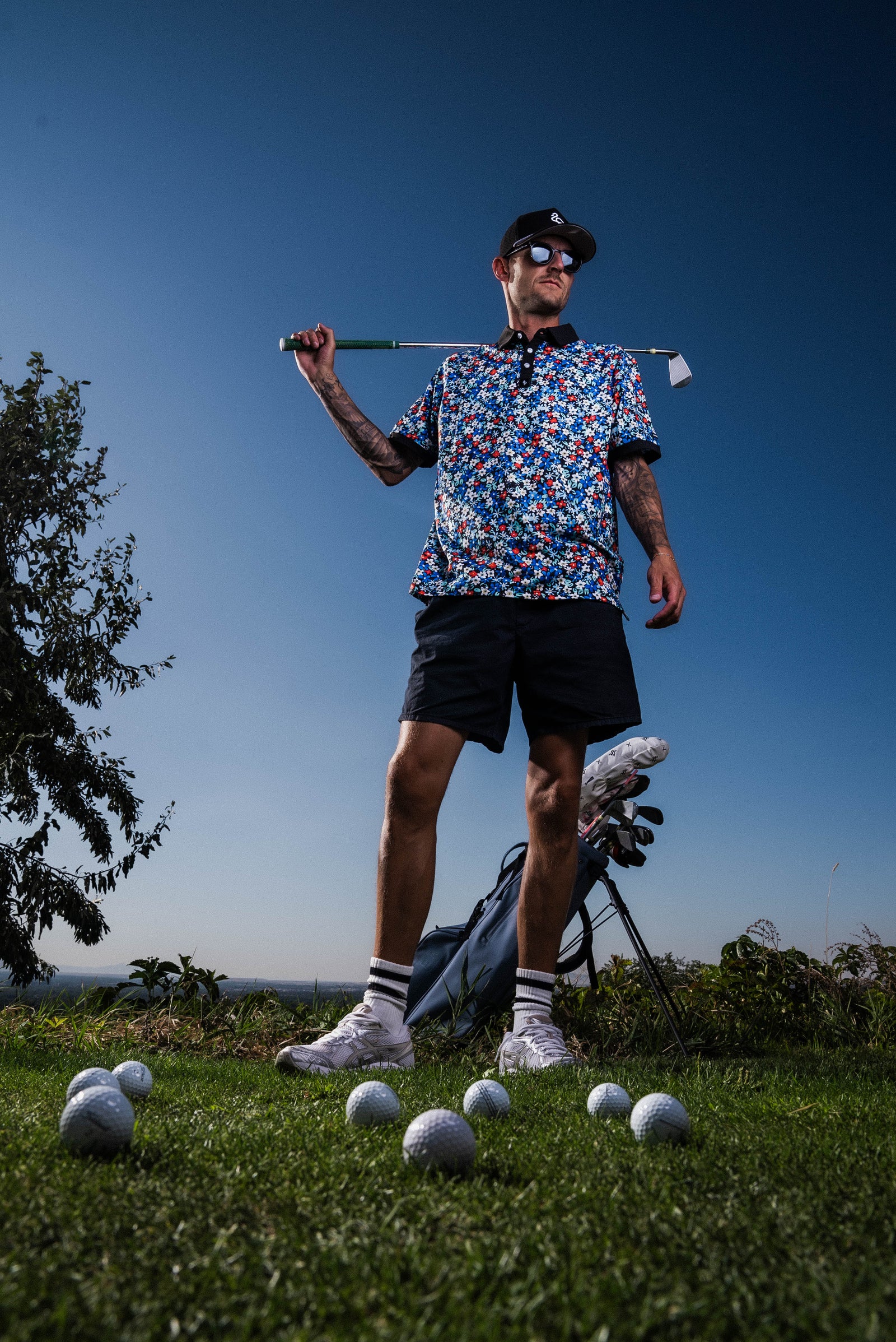 Men’s white polo with delicate pastel flower print – subtle floral detail, breathable, stretch-performance shirt.