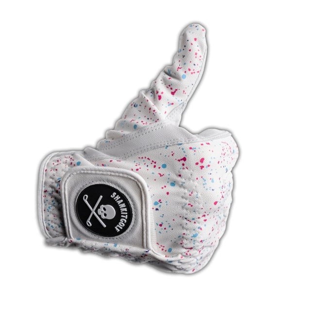 White Cabretta leather golf glove with multicolor paint splatter design and padded palm, displayed on thumbs-up hand form with branded patch.