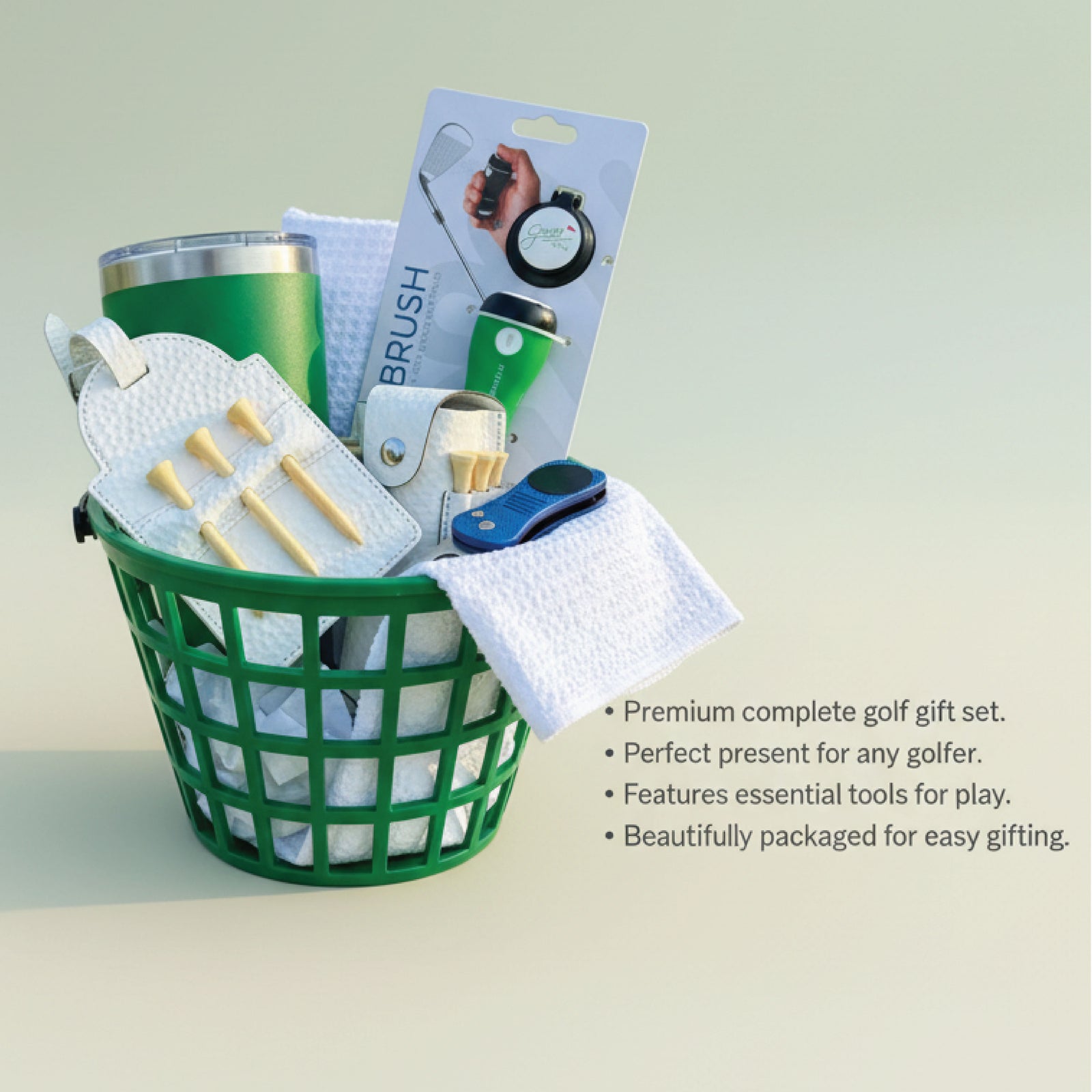 Green mesh basket filled with golf accessories including a green tumbler, white waffle towel, wooden tees, club brush, divot tool, ball marker, and packaging displayed on neutral background.