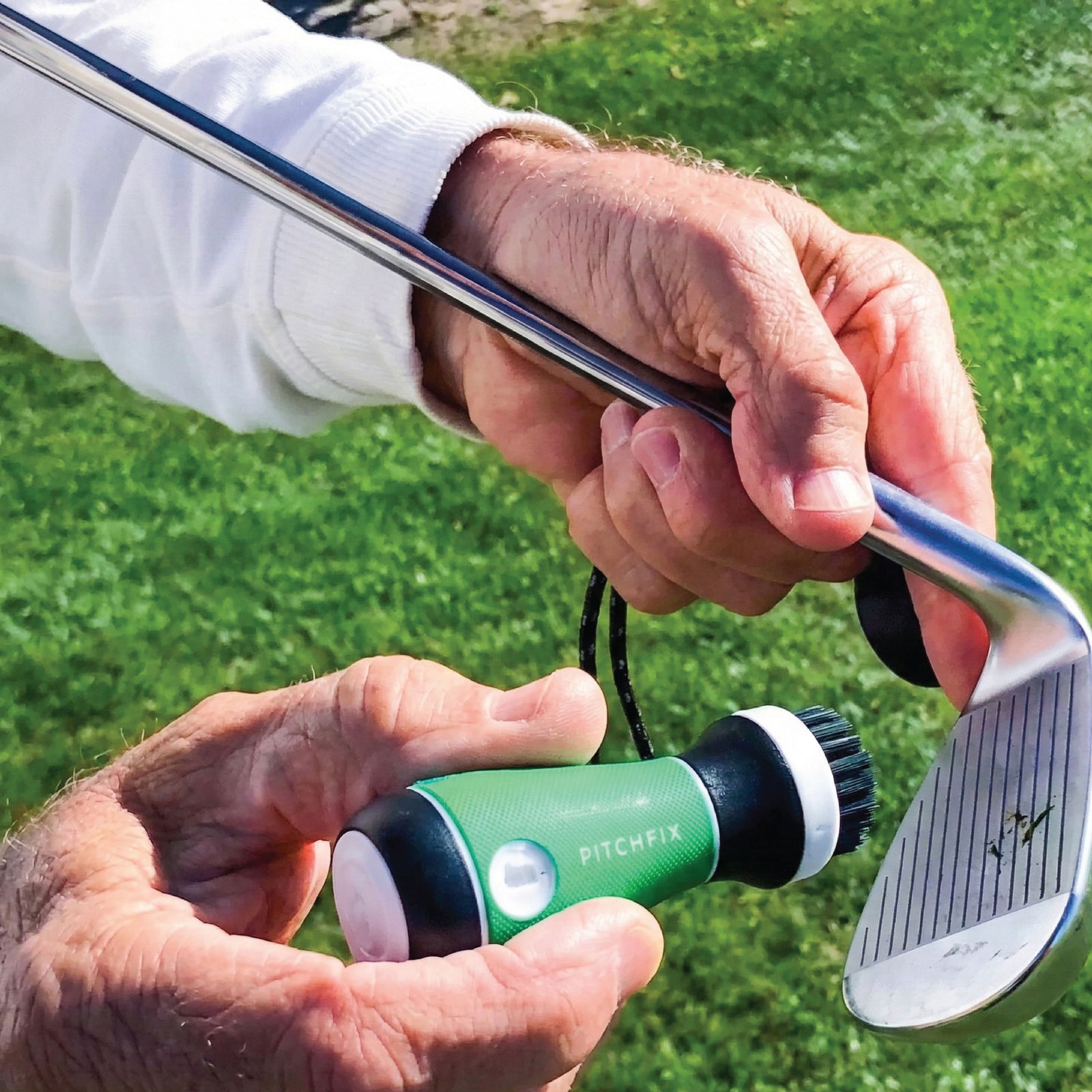 Golfer holding green ball marker and divot tool in one hand while gripping putter with the other, demonstrating compact size on the golf course.