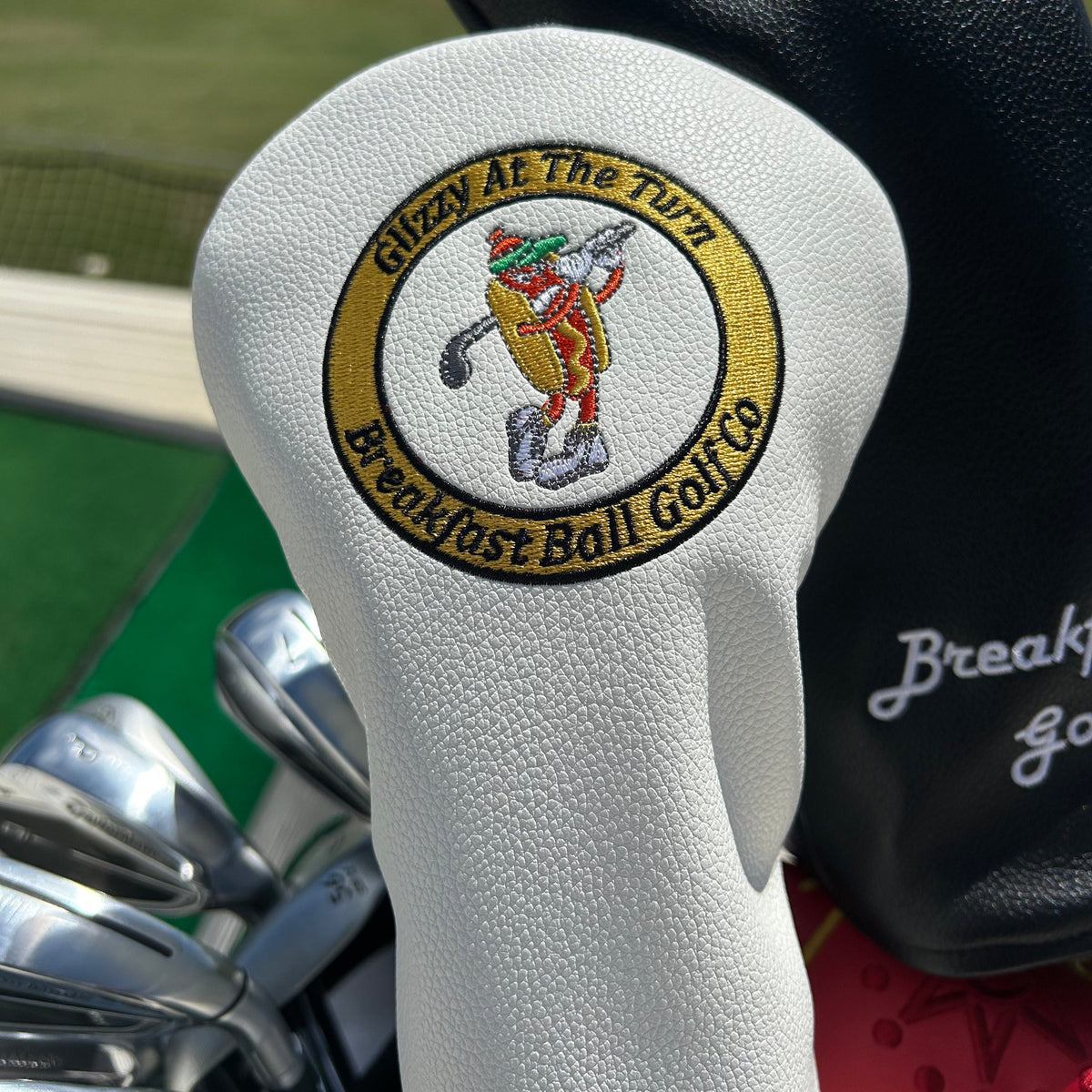 Close-up of golf club heads with visible branding on a grassy background