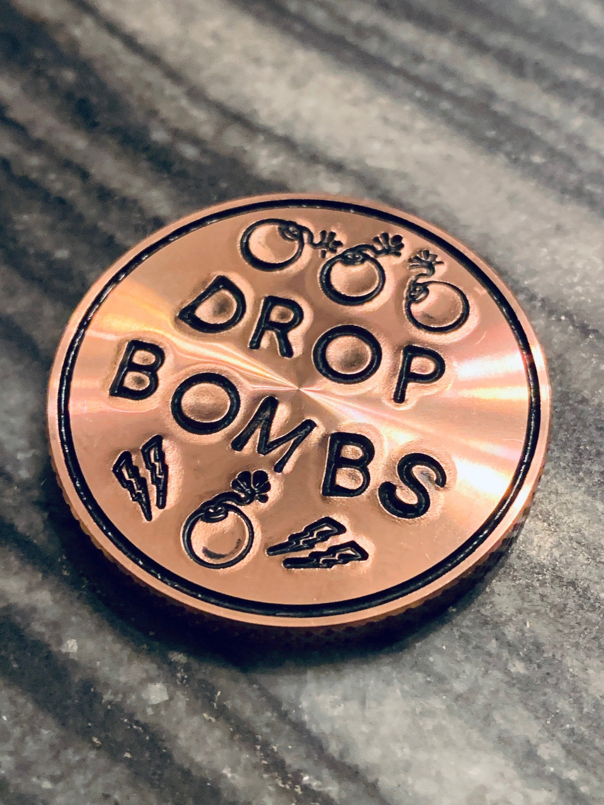 Copper golf ball marker engraved with Drop Bombs