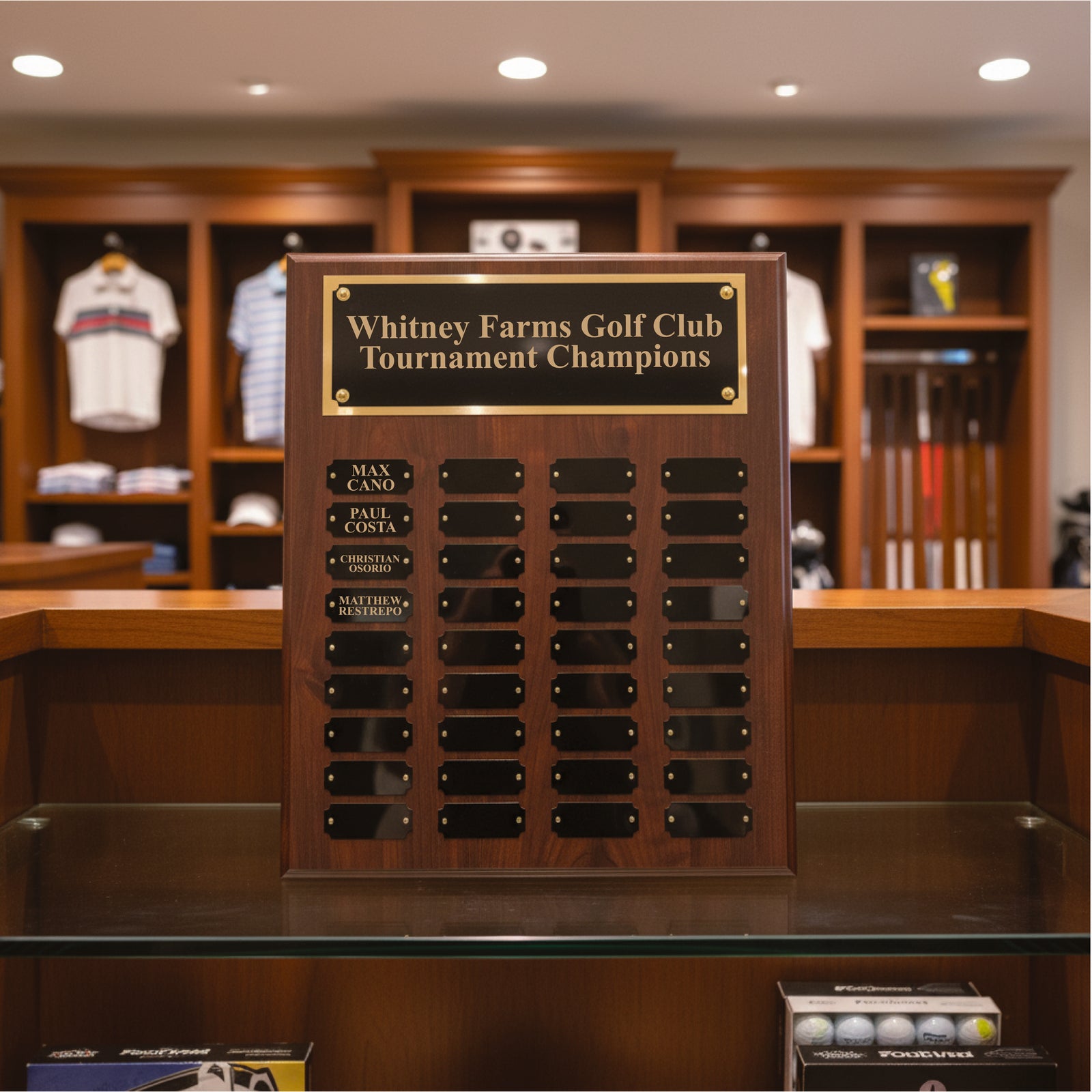 Wooden perpetual plaque with engraved gold header reading "Whitney Farms Golf Club Tournament Champions" and black nameplate plaques arranged in rows below