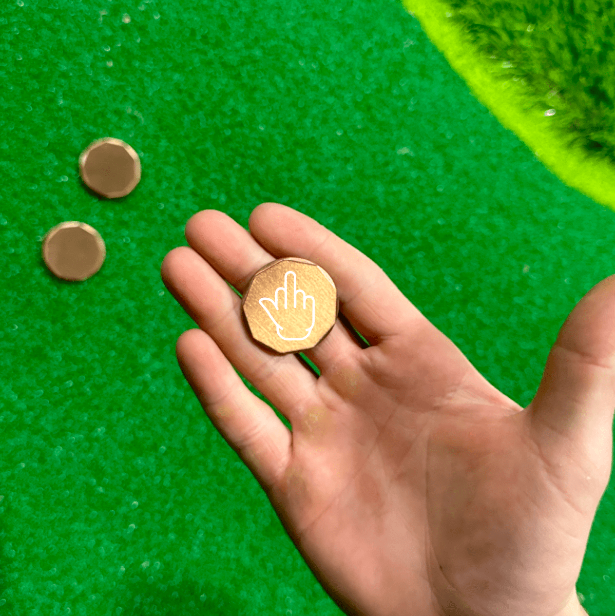 Copper golf ball marker with middle finger engraving, adds humor to any golf game.