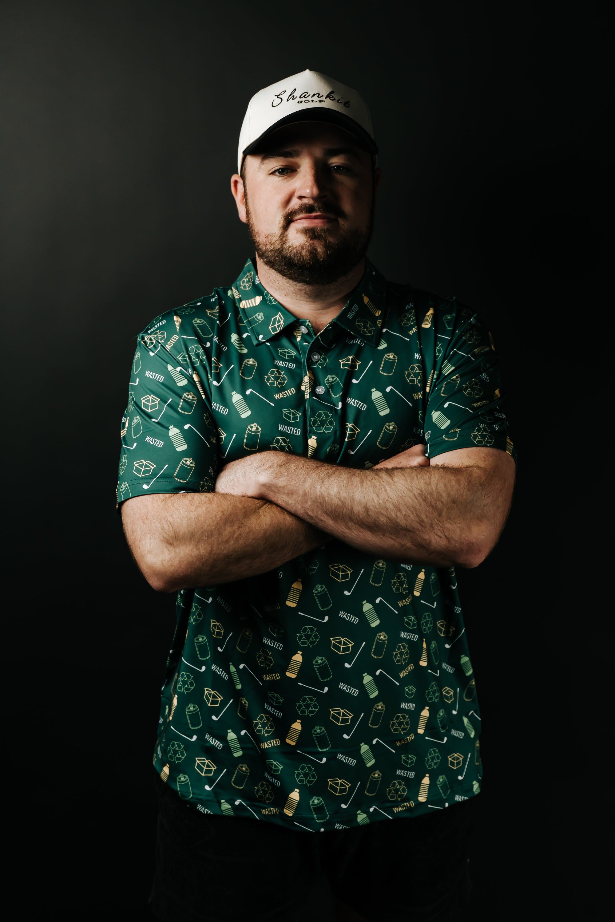 Man wearing a green patterned shirt and white cap against a black background