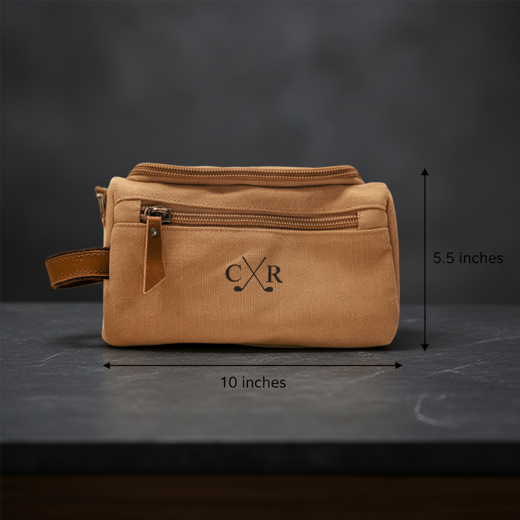 Tan canvas toiletry bag with leather handle and zipper pulls, embroidered with sample initials "CXR" and crossed golf clubs design, shown with dimensions of 10 by 5.5 inches
