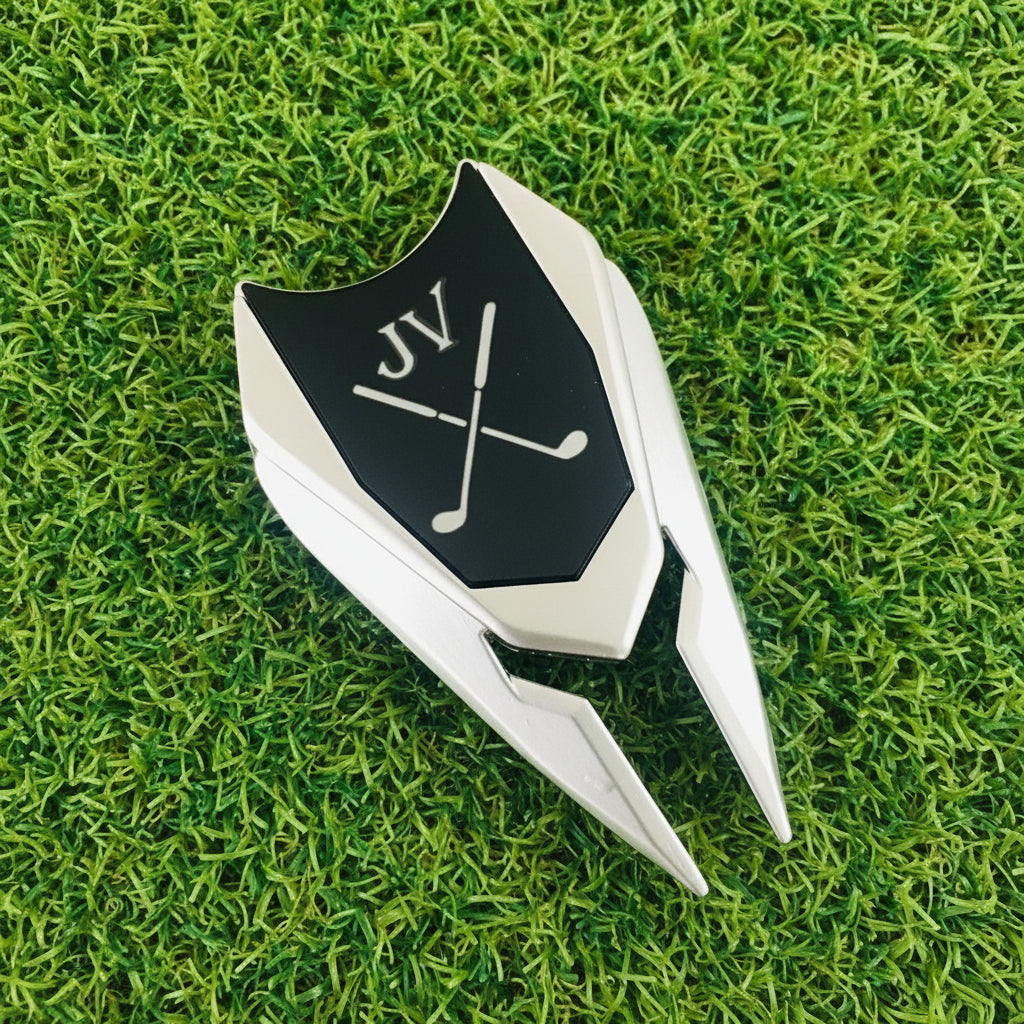Real photo of the Earth Adjuster personalized golf divot tool on the grass, the black marker engraved with initials above crossed golf clubs