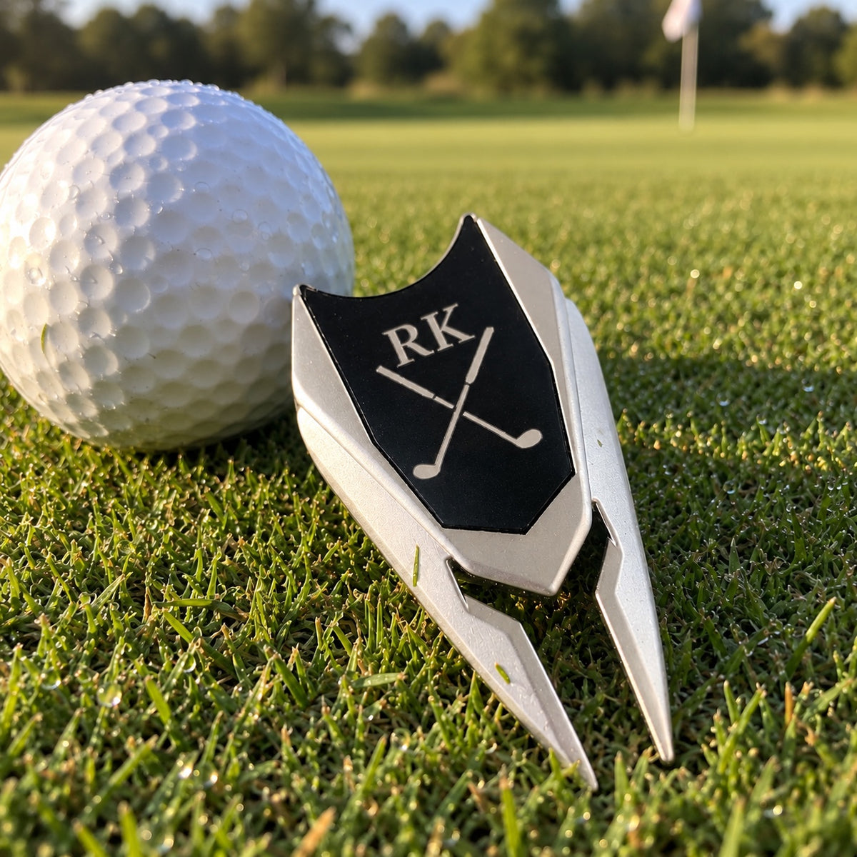 Earth Adjuster golf divot tool on a putting green, the black pop-out ball marker engraved with the initials RK above two crossed golf clubs