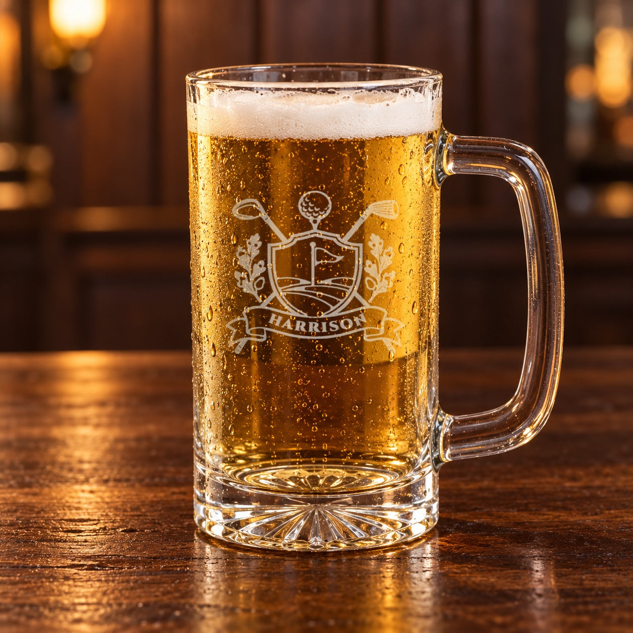 Close-up of a golf beer mug full of lager, etched with a golf crest of crossed clubs, a flag and a ball on a tee over the name HARRISON