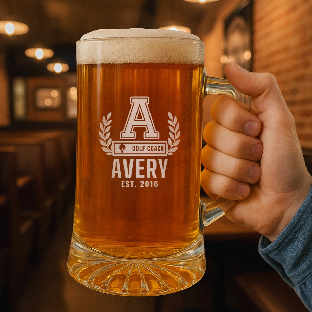 Hand holding a personalized golf coach beer stein engraved with a varsity A, laurel wreath and AVERY, a thank-you gift for a head golf coach