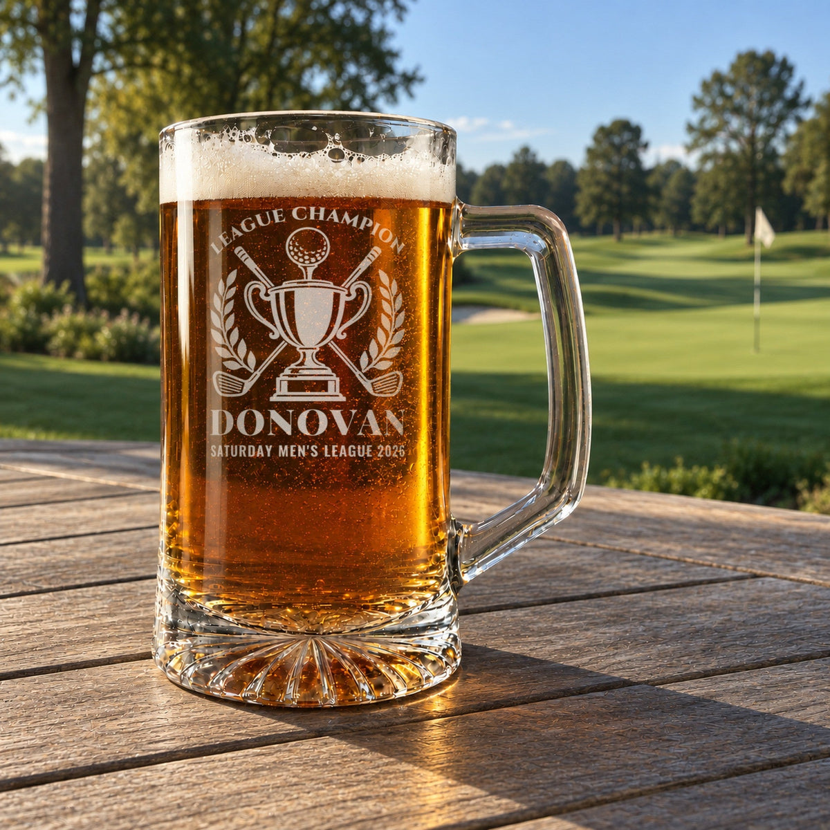 Golf league champion beer stein on a clubhouse patio table overlooking a green fairway and flag, engraved League Champion, Donovan, Saturday Men's League 2026