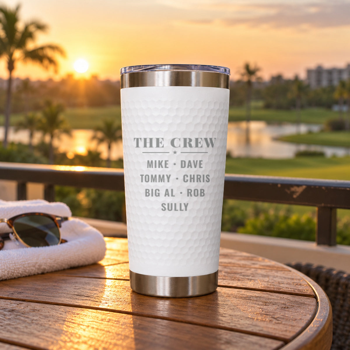 Back of a white golf trip tumbler engraved THE CREW with seven names, Mike, Dave, Tommy, Chris, Big Al, Rob and Sully, on a balcony