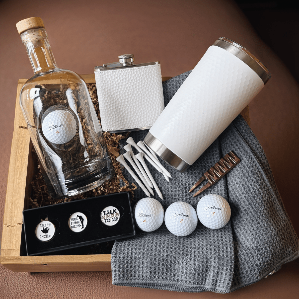 Wooden crate Filled with personalized golf gear including a tumbler, flask, decanter, ball markers, tees, towel, divot tool, and golf balls 