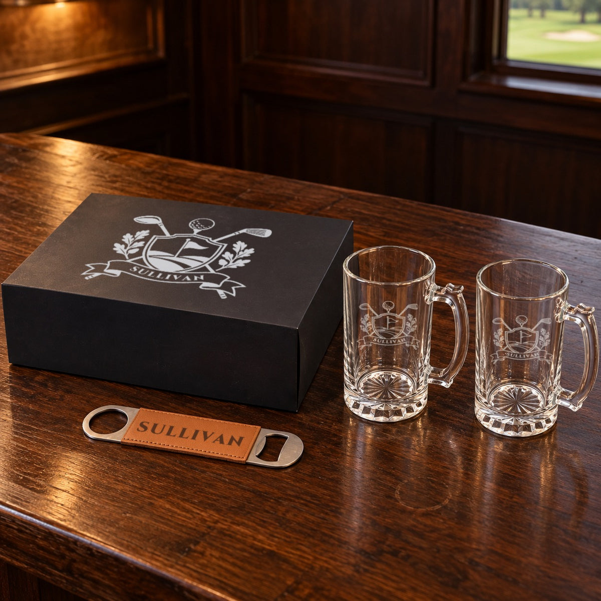 Personalized golf beer mug gift set: black gift box lid engraved with a golf crest and SULLIVAN, two etched glass beer mugs and a bottle opener