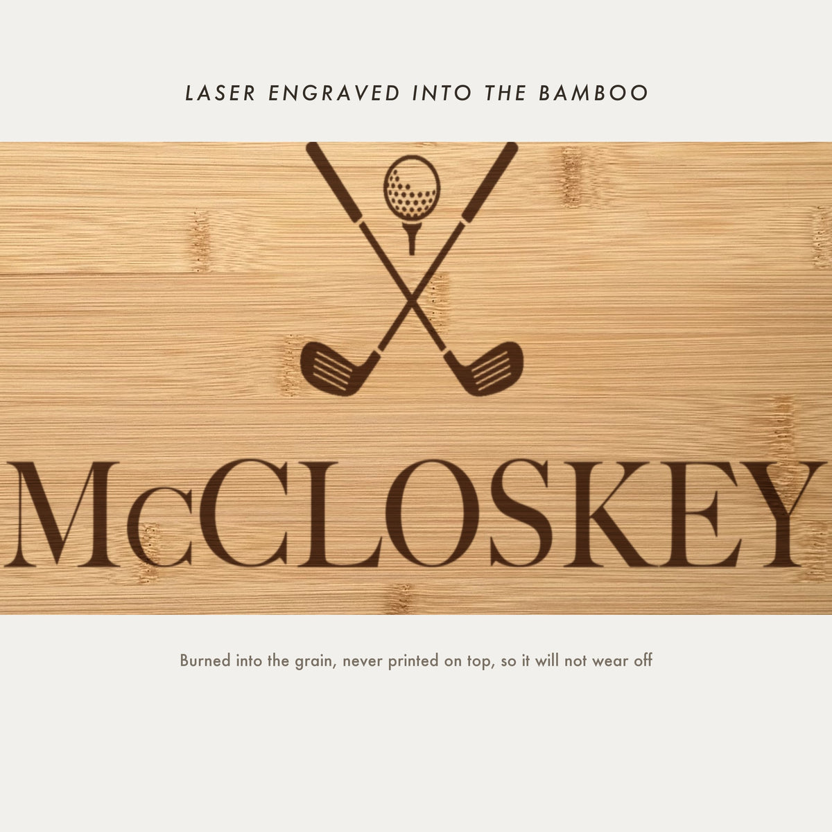 Close view of the crossed golf clubs and ball on a tee laser engraved into the bamboo grain above the family name in a high contrast serif.