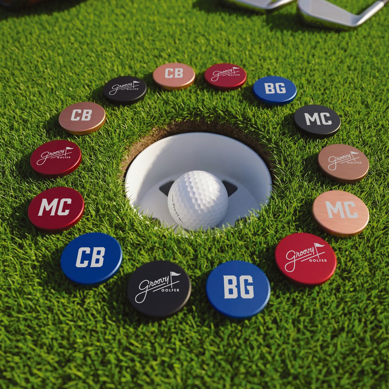 Collection of customized ball markers in multiple colors arranged around a golf cup on synthetic green, showing sample initials and names including CB, BG, and MC